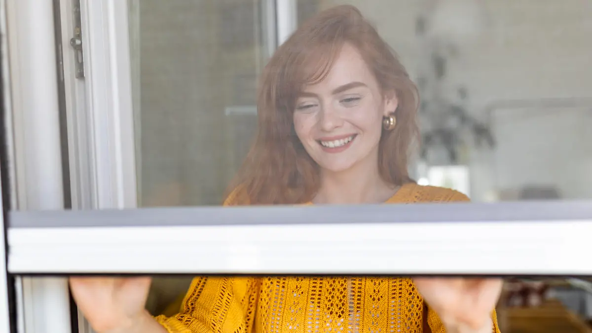 Woman hand hold retractable pleated insect screen holder to open or close the window ,mosquito nets