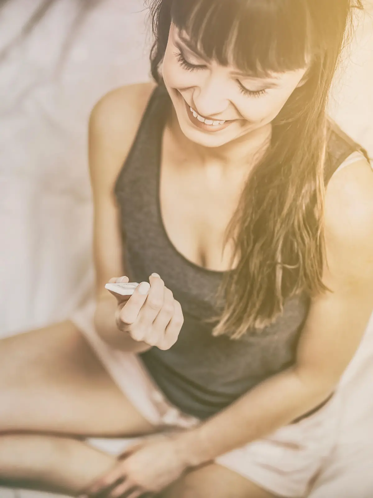 Young beautiful woman holding a pregnancy test. Enjoys a positive result. He is happy because he will be a mom.