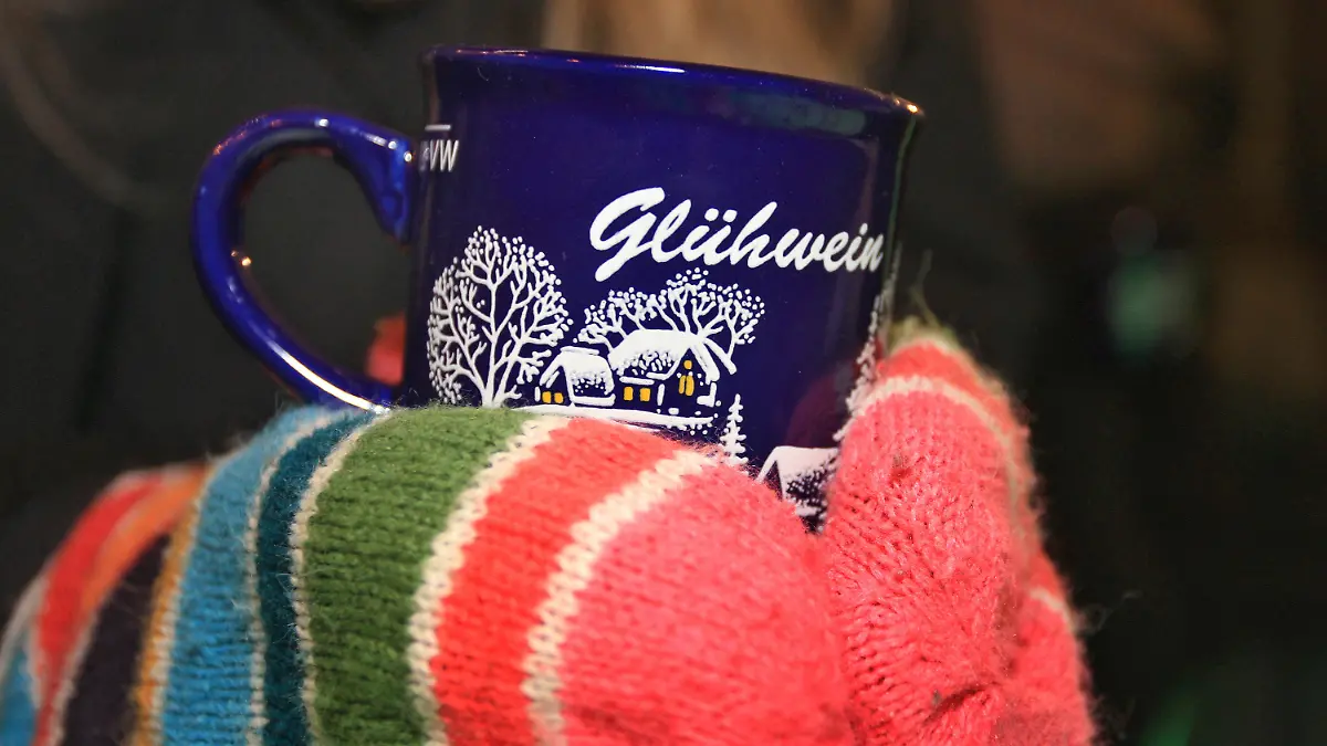 Hände in bunten Wollhandschuhen halten am 03.12.2013 auf dem Weihnachtsmarkt in Kempten (Bayern) eine Tasse mit Glühwein. Foto: Karl-Josef Hildenbrand/dpa +++(c) dpa - Bildfunk+++