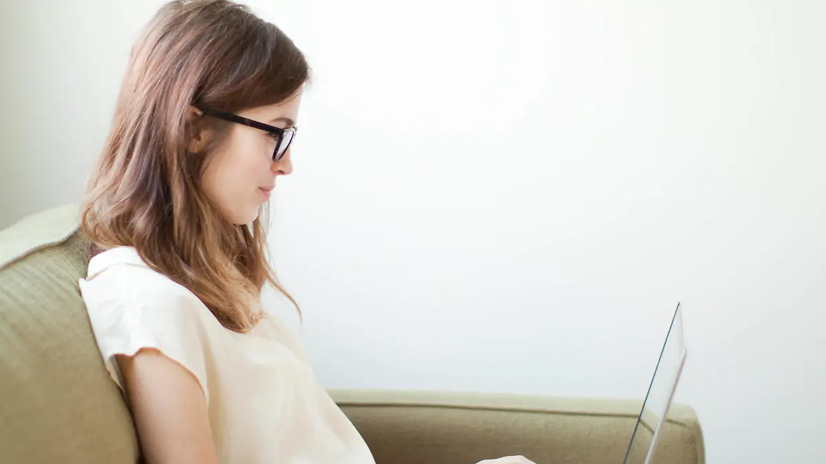 Young woman sitting on sofa with laptop, Junge Frau, die auf der Couch mit dem Laptop sitzt Keine Weitergabe an Drittverwerter.