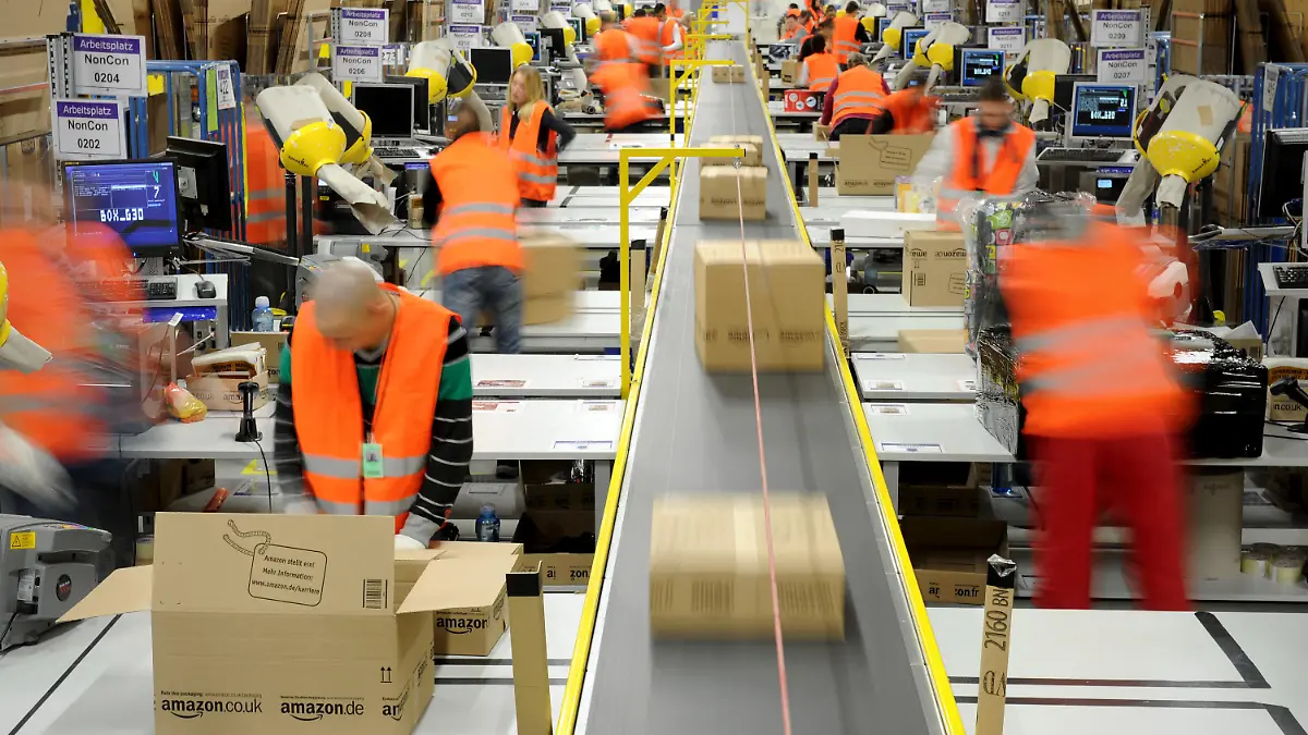 ARCHIV - Mitarbeiter der Versandabteilung des Amazon Logistik-Zentrums in Pforzheim (Baden-Württemberg), verpacken am 11.12.2012 Waren in Pakete (Aufnahme mit Langzeitbelichtung). Der Einzelhandel unterliegt einem ständigen Wandel. Durch den Boom des Online-Handels sind die stationären Händler noch mehr gefordert, ihren Laden am Laufen zu halten. Foto: Jan-Philipp Strobel/dpa (zu dpa «Einzelhandelsverband: Online-Handel bedroht Innenstädte nicht» vom 12.02.2013) +++(c) dpa - Bildfunk+++