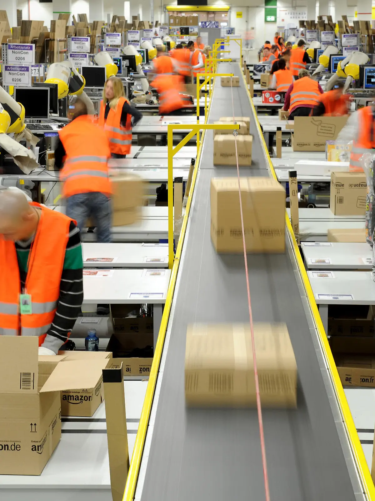 ARCHIV - Mitarbeiter der Versandabteilung des Amazon Logistik-Zentrums in Pforzheim (Baden-Württemberg), verpacken am 11.12.2012 Waren in Pakete (Aufnahme mit Langzeitbelichtung). Der Einzelhandel unterliegt einem ständigen Wandel. Durch den Boom des Online-Handels sind die stationären Händler noch mehr gefordert, ihren Laden am Laufen zu halten. Foto: Jan-Philipp Strobel/dpa (zu dpa «Einzelhandelsverband: Online-Handel bedroht Innenstädte nicht» vom 12.02.2013) +++(c) dpa - Bildfunk+++