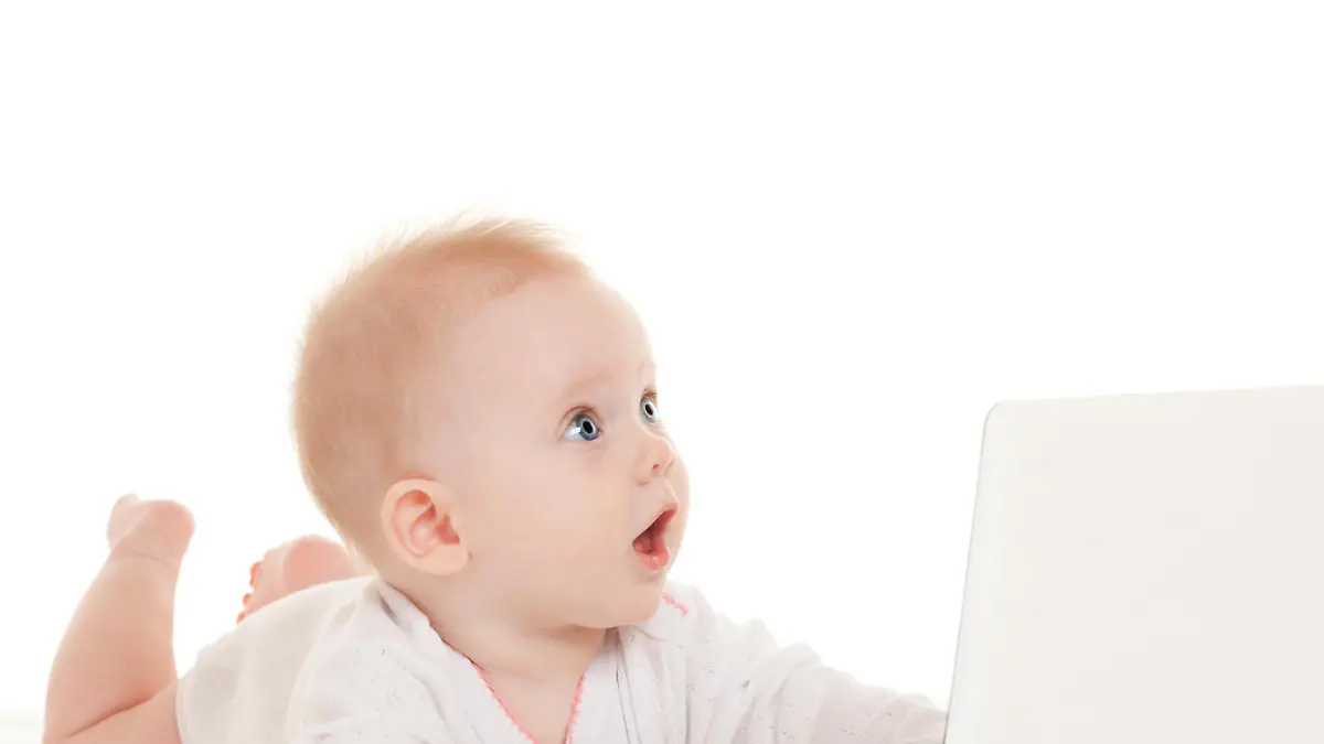 Cute baby with laptop on the white bed