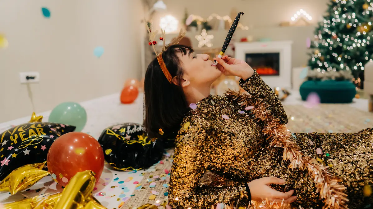 Photo of a young woman lying down on the floor of her living room after the New Year's Eve party