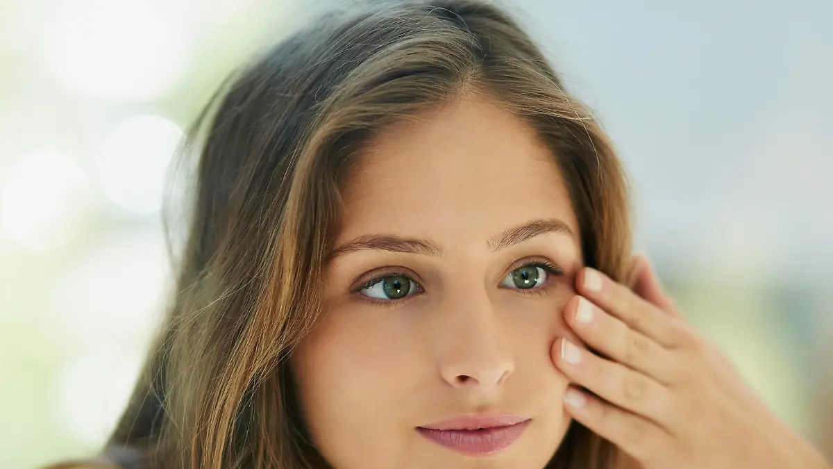 Shot of an attractive young woman touching her skin in front of the mirror