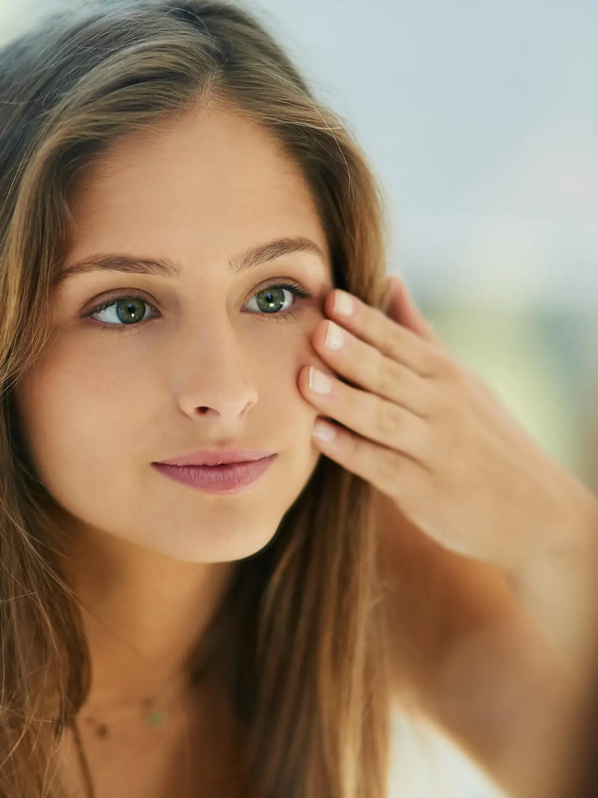 Shot of an attractive young woman touching her skin in front of the mirror