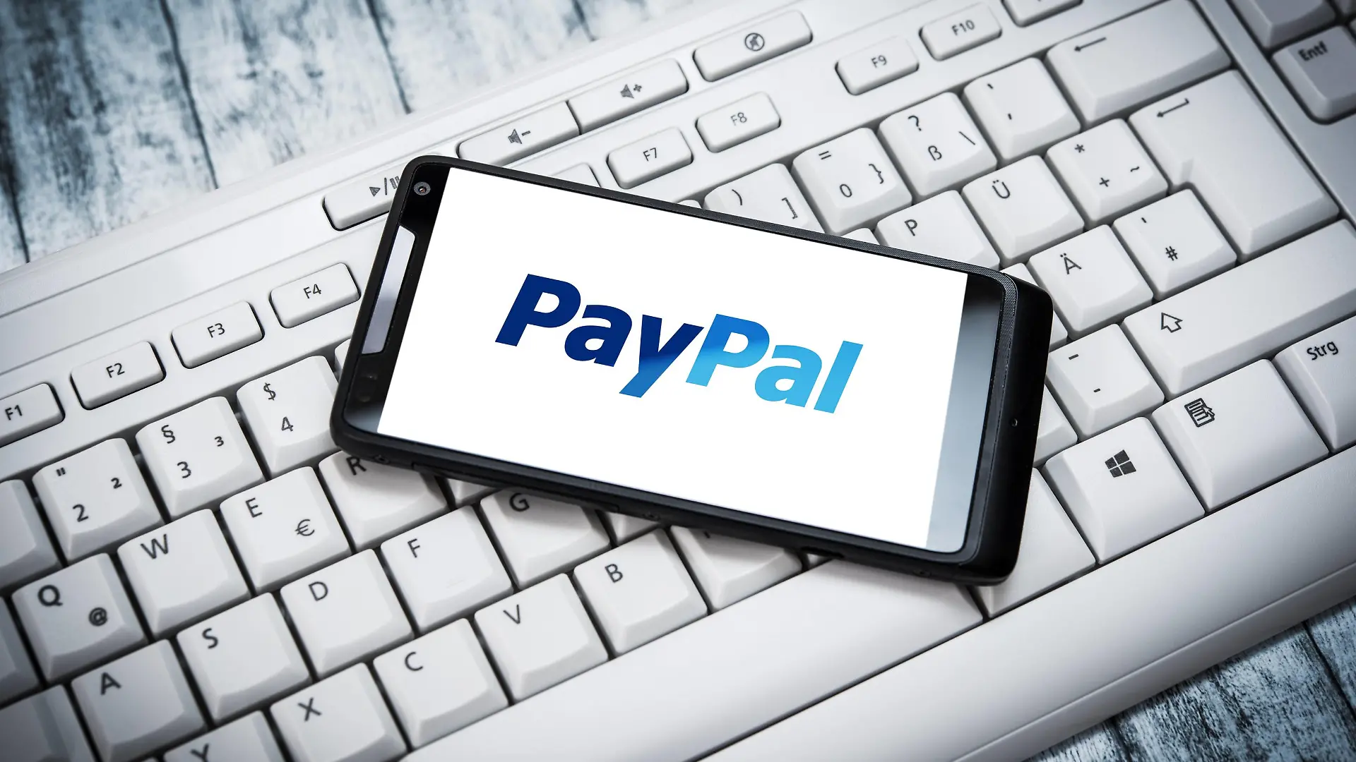 Smarphone mit PayPal-App liegt auf einer Computer-Tastatur.