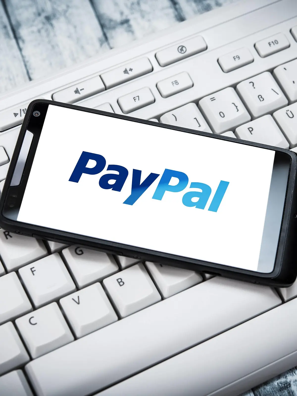 Smarphone mit PayPal-App liegt auf einer Computer-Tastatur.