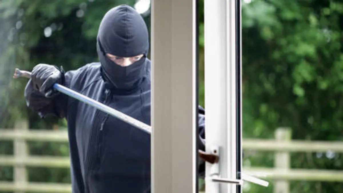 Burglar breaking into a house window with a crowbar