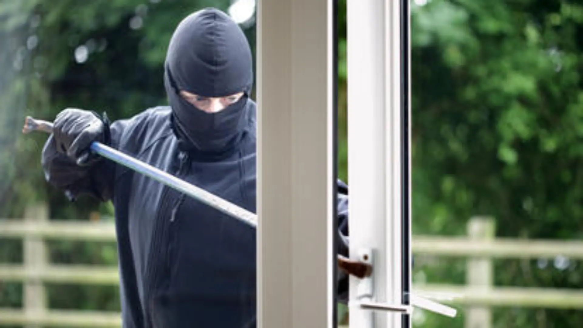 Burglar breaking into a house window with a crowbar
