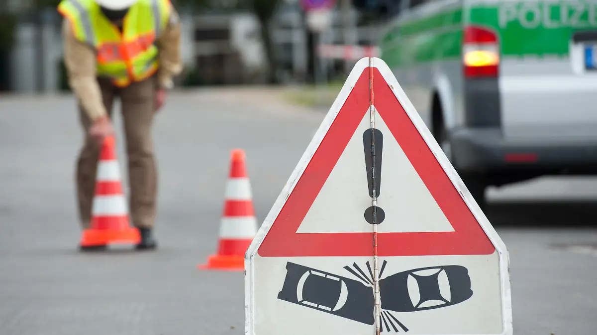 ILLUSTRATION - Ein Polizist steht hinter einem Unfall-Warnschild, aufgenommen am 11.10.2011 in Straubing (Niederbayern). Viele Autofahrer bezahlen zu viel Geld für ihre Autoversicherung. Foto: Armin Weigel dpa/lby +++(c) dpa - Bildfunk+++