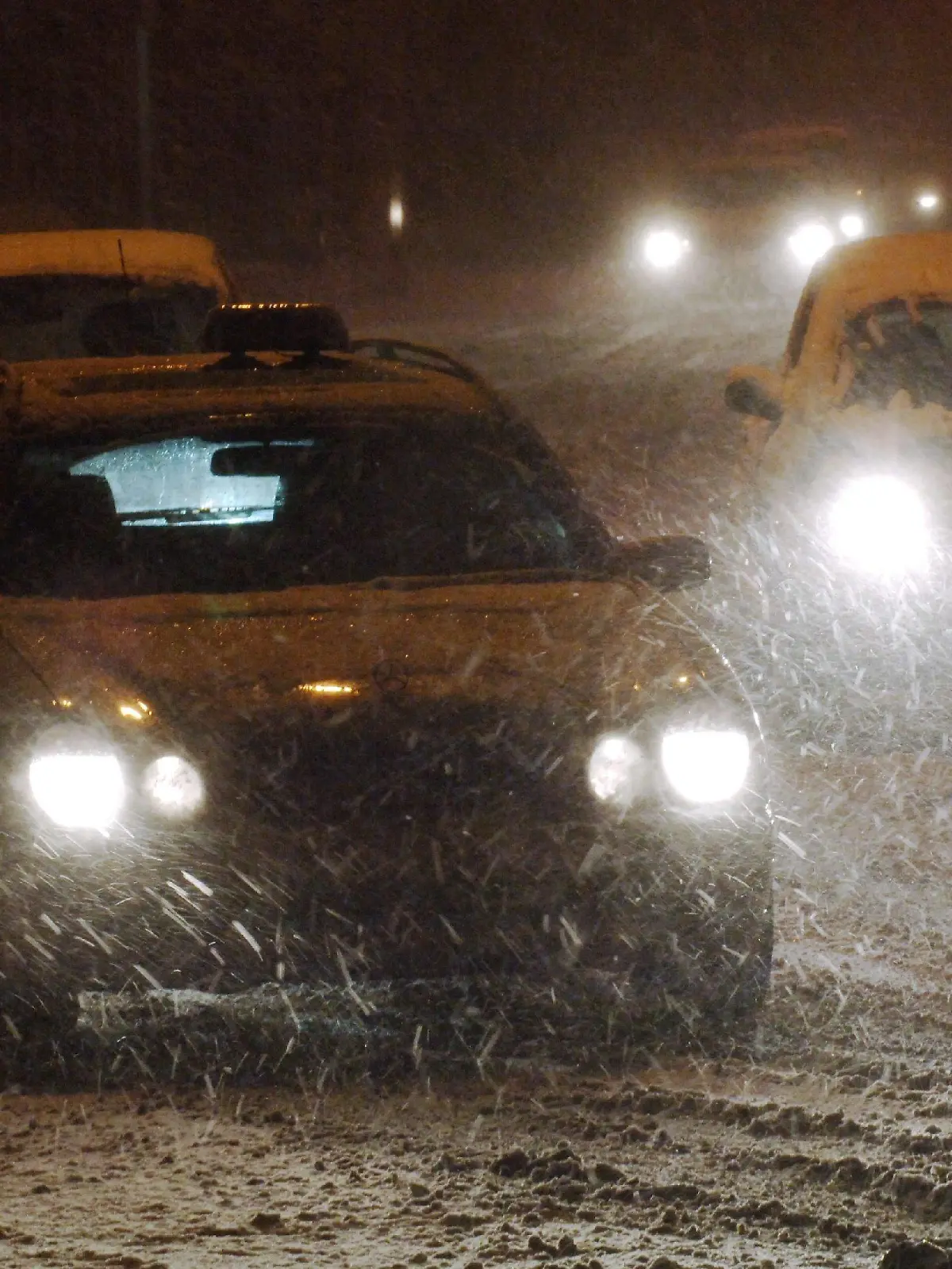Autofahrer bewegen sich in der Nacht zum Freitag (25.11.2005) in der Innenstadt von Frankfurt am Main auf einer verschneiten Straße. Tief "Thorsten" sorgt in den Niederungen für eine Schneedecke von bis zu fünf Zentimetern. Autofahrer müssen sich deshalb im Berufsverkehr auf die ersten Rutschpartien auf Schnee und Eis einstellen. Foto: Arne Dedert dpa/lhe +++(c) dpa - Bildfunk+++