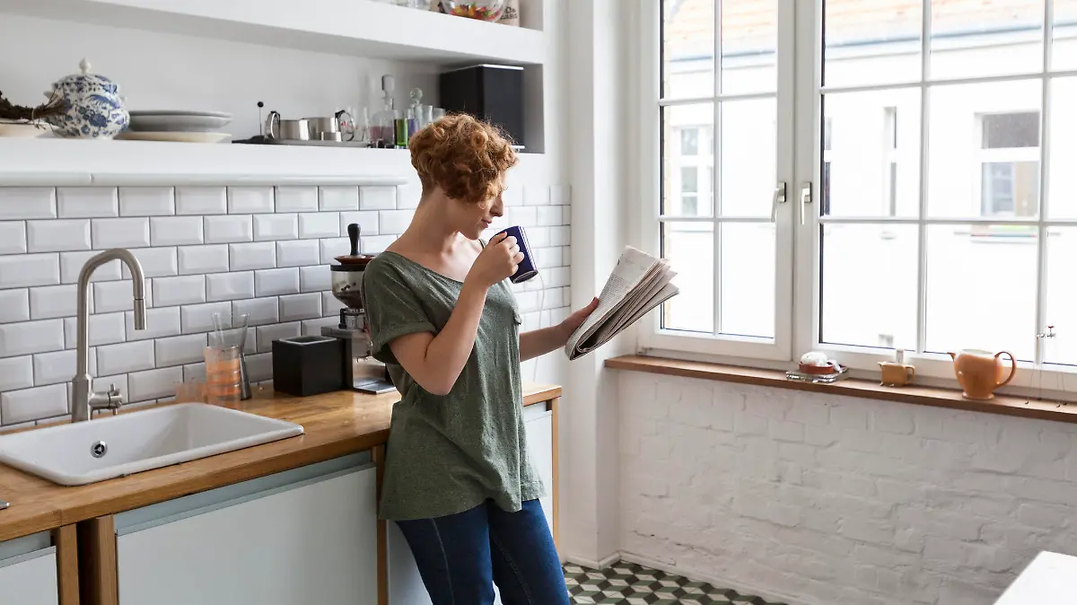 Frau liest Horoskop und trinkt Kaffee