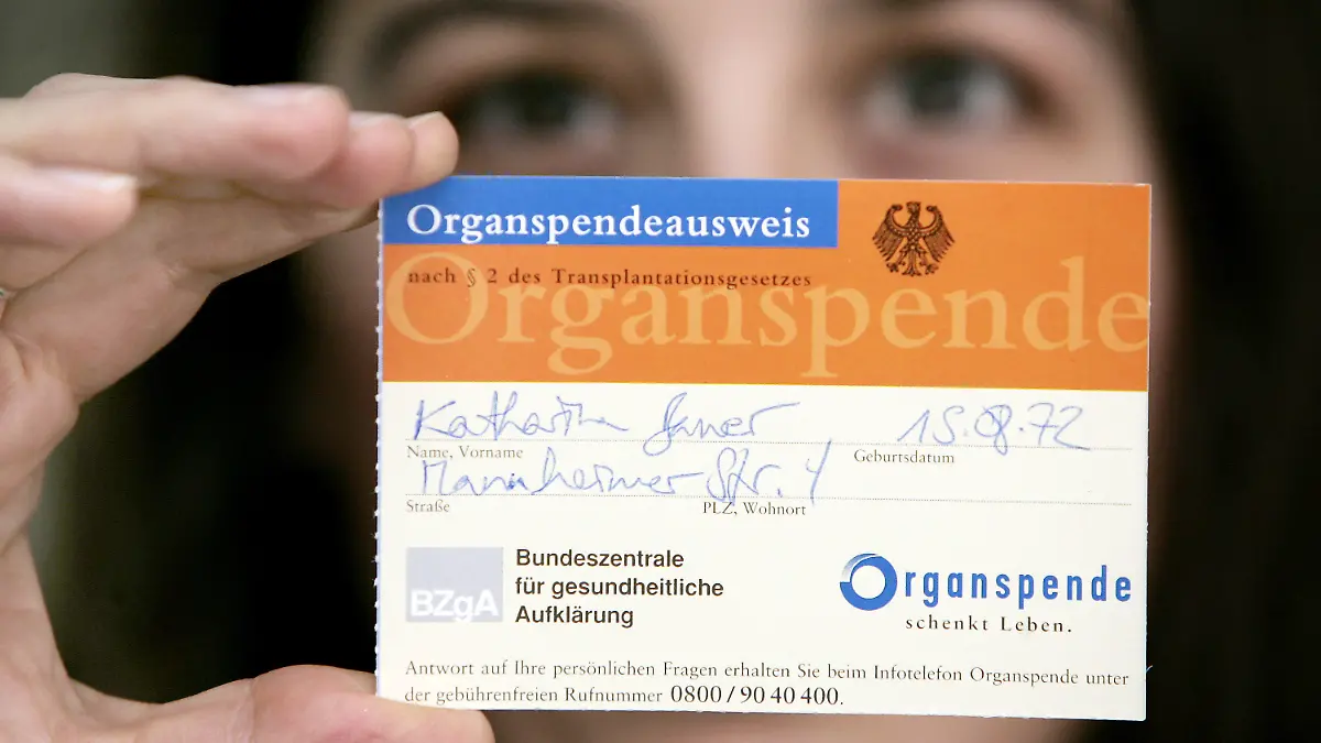 ARCHIV - Eine junge Frau zeigt in Frankfurt/Main einen Organspenderausweis (Archivfoto vom 18.02.2005). Der Bundestag entscheidet heute (25.05.2012) über die Organspende-Reform. Derzeit warten rund 12 000 Menschen auf ein Organ. Dennoch hat nur eine Minderheit der Bundesbürger einen Organspendeausweis ausgefüllt. Künftig soll die Entscheidungslösung gelten: Alle Bürger sollen von ihren Krankenkassen schriftlich gefragt werden, ob sie nach dem Hirntod zur Spende bereit sind.  Foto: Frank May dpa  +++(c) dpa - Bildfunk+++