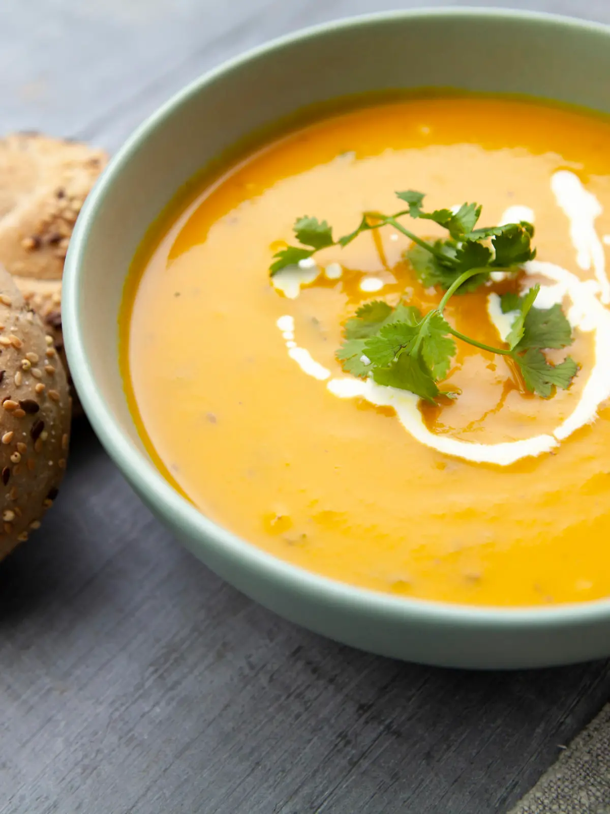 Healthy meal of carrot and coriander soup with bread rolls - photographed in a rustic setting