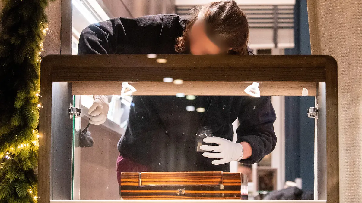 20.12.2022, Hamburg: Eine Mitarbeiterin der Spurensicherung der Polizei untersucht nach einem Überfall auf einen Juwelier in der Neustadt eine Vitrine. Mehrere Täter haben am Abend das Geschäft überfallen und dabei Schmuck und Uhren in Wert mehrerer Millionen erbeutet. Foto: Daniel Bockwoldt/dpa - ACHTUNG: Die Person wurde auf ihren Wunsch hin gepixelt +++ dpa-Bildfunk +++