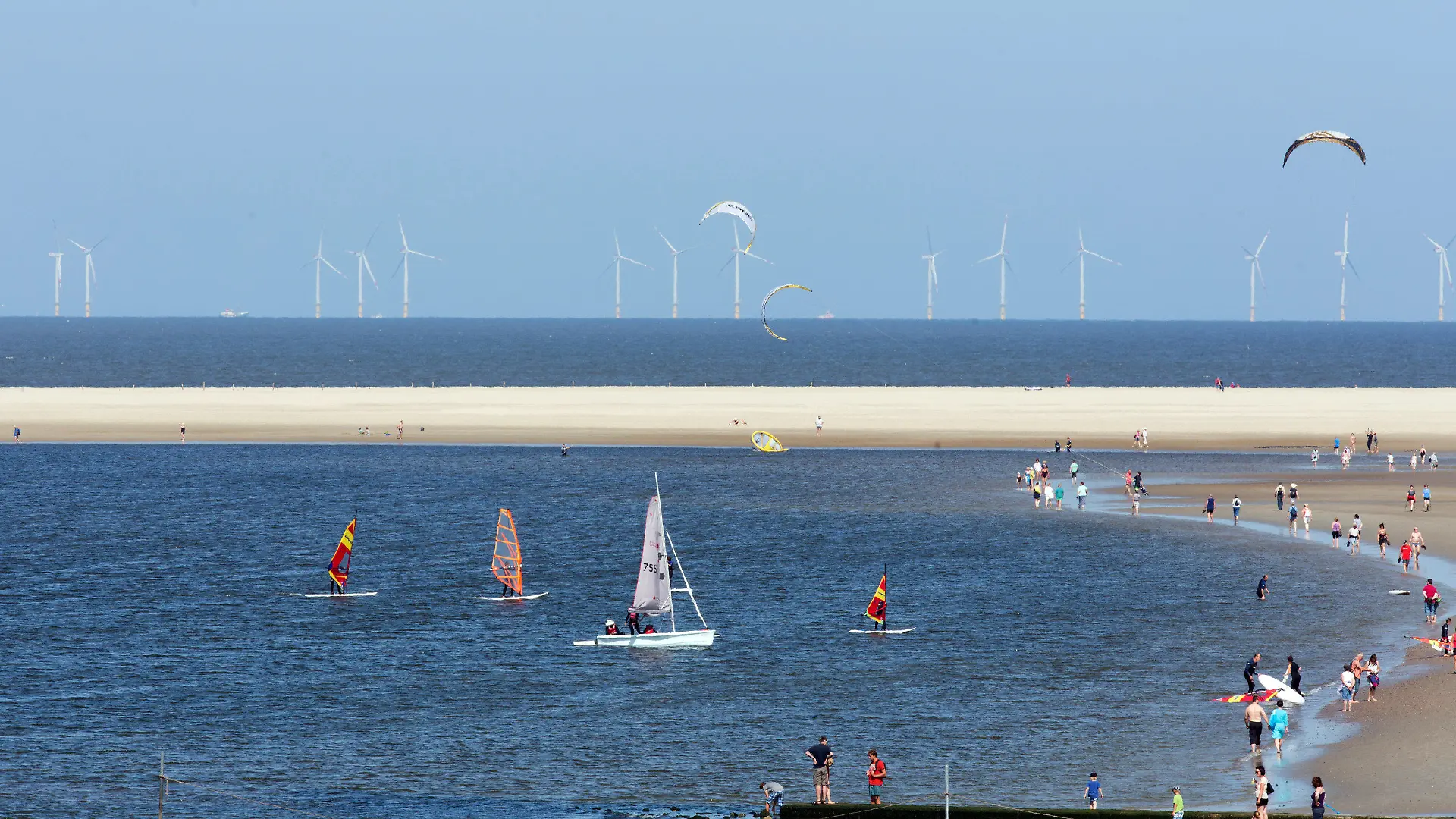 Urlauber vertreiben sich am 19.07.2013 am Strand der Nordseeinsel Borkum (Niedersachsen) die Zeit bei sonnigem Sommerwetter. Am Horizont ist der Offshore-Windpark Riffgat zu sehen. Foto: Joerg Sarbach/dpa +++(c) dpa - Bildfunk+++