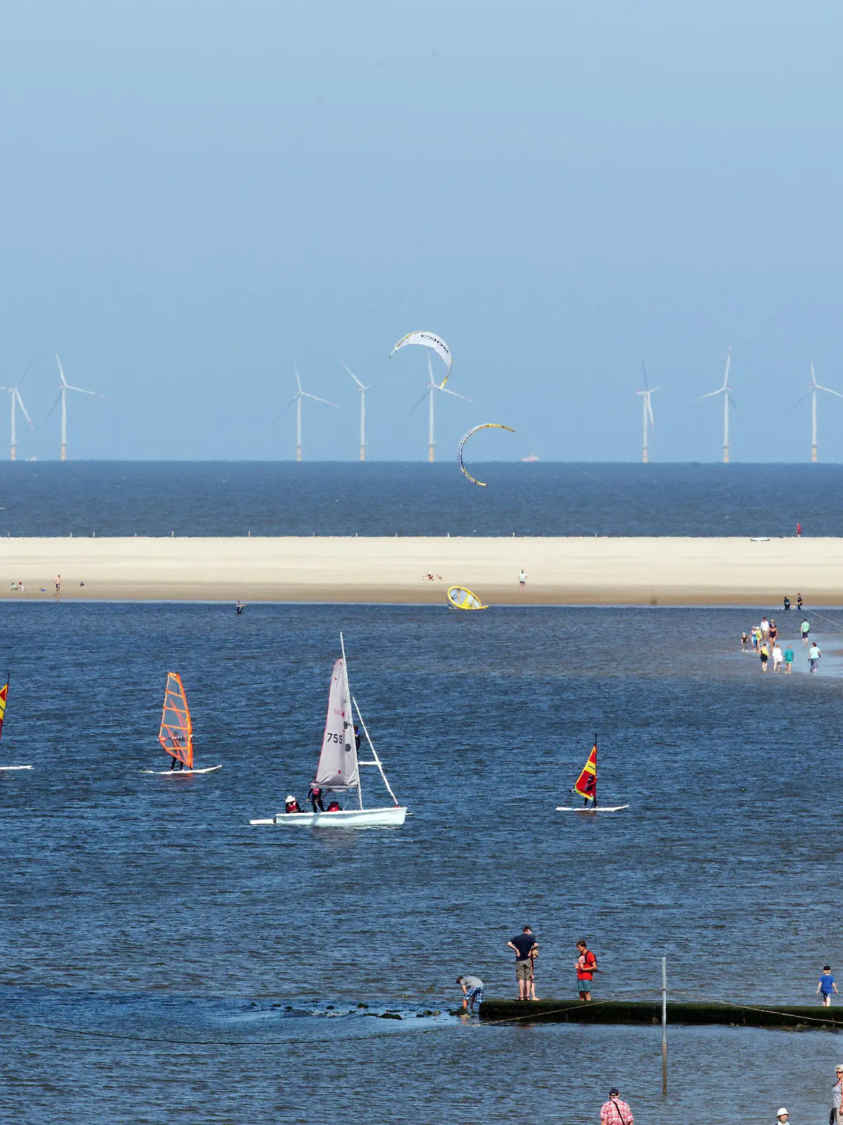 Urlauber vertreiben sich am 19.07.2013 am Strand der Nordseeinsel Borkum (Niedersachsen) die Zeit bei sonnigem Sommerwetter. Am Horizont ist der Offshore-Windpark Riffgat zu sehen. Foto: Joerg Sarbach/dpa +++(c) dpa - Bildfunk+++