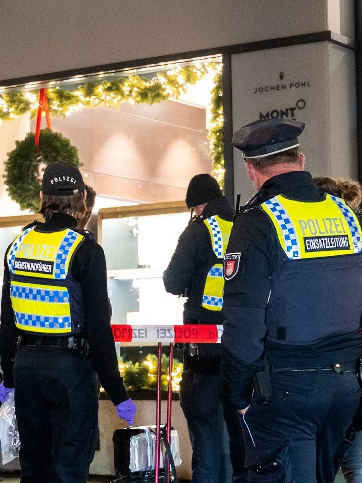 20.12.2022, Hamburg: Polizisten stehen nach einem Überfall auf einen Juwelier in der Neustadt vor dem Gebäude. Mehrere Täter haben am Abend das Geschäft überfallen und dabei Schmuck und Uhren in Wert mehrerer Millionen erbeutet. Foto: Daniel Bockwoldt/dpa +++ dpa-Bildfunk +++