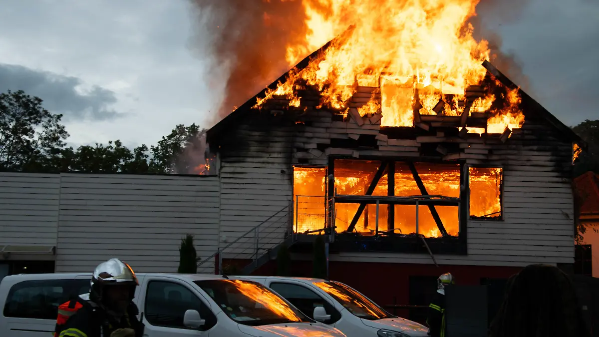 09.08.2023, Frankreich, Wintzenheim: Feuerwehrleute löschen einen Brand in einer Ferienunterkunft. Elf Menschen wurden nach dem Feuer vermisst. Frankreichs Innenminister Gerald Darmanin zufolge beherbergt die Stätte behinderte Menschen. Die Präfektur schrieb, dass sich eine Erwachsenengruppe aus Nancy für die Ferien in der Unterkunft aufhielt. Foto: Patrick Kerber/dpa +++ dpa-Bildfunk +++