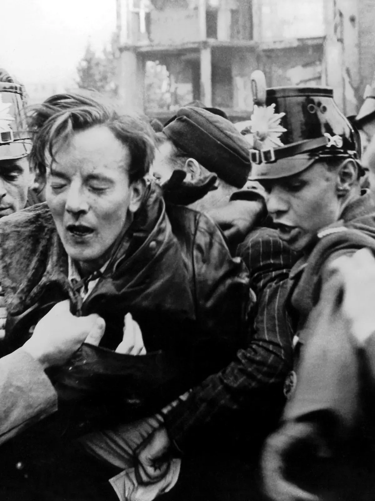 Ein kommunistischer Agitator, der von der demonstrierenden Menschenmenge zusammengeschlagen wurde, wird an der Sektorengrenze von Westberliner Polizisten geschützt. Blick vom amerikanischen Sektor in die Ostberliner Friedrichstraße, auf der ein Zeitungskiosk in Flammen steht. Nach Streiks in Ost-Berlin kam es am 17. Juni 1953 zum Volksaufstand in der DDR, der von sowjetischen Truppen niedergeschlagen wurde.