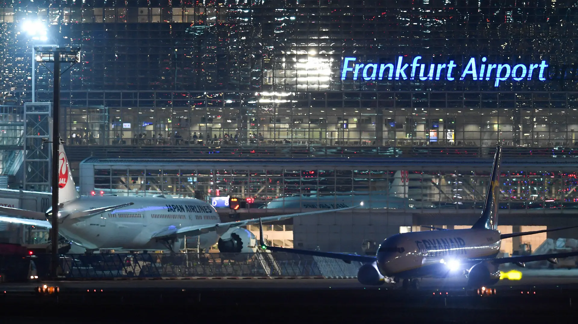 ARCHIV - 17.03.2020, Hessen, Frankfurt/Main: Eine Passagiermaschine der Ryanair (r) rollt nach Sonnenuntergang am Terminal 2 des Frankfurter Flughafens neben einem Flugzeug der Japan Airlines zur Startbahn. Auch nach der Eröffnung des neuen Terminals 3 wird der Frankfurter Flughafen eine Dauerbaustelle bleiben. Betreiber Fraport will die zum Sommer 2026 hinzukommende jährliche Abfertigungskapazität von rund 19 Millionen Passagieren nutzen, um das Terminal 2 grundlegend technisch zu sanieren, wie das Unternehmen erklärte. Foto: Arne Dedert/dpa +++ dpa-Bildfunk +++