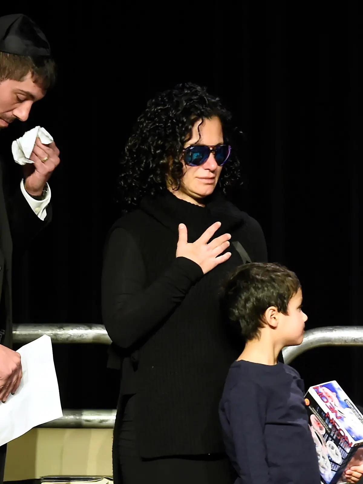 FILE - In this Dec. 21, 2017 file photo, Jonathon Sherman wipes his tears as he and his sister Lauren walk to the stage during a memorial service in Mississauga, Ontario, for their parents Barry and Honey Sherman, who were found dead inside their mansion. The day after the bodies were discovered, prominent media outlets quoted unnamed police sources as saying it appeared to be a murder-suicide. The family blasted the Toronto police as “irresponsible” for the early reports of a murder-suicide, and hired their own investigator and pathologist to conduct second autopsies on Barry and Honey Sherman. (Nathan Denette/The Canadian Press via AP File)