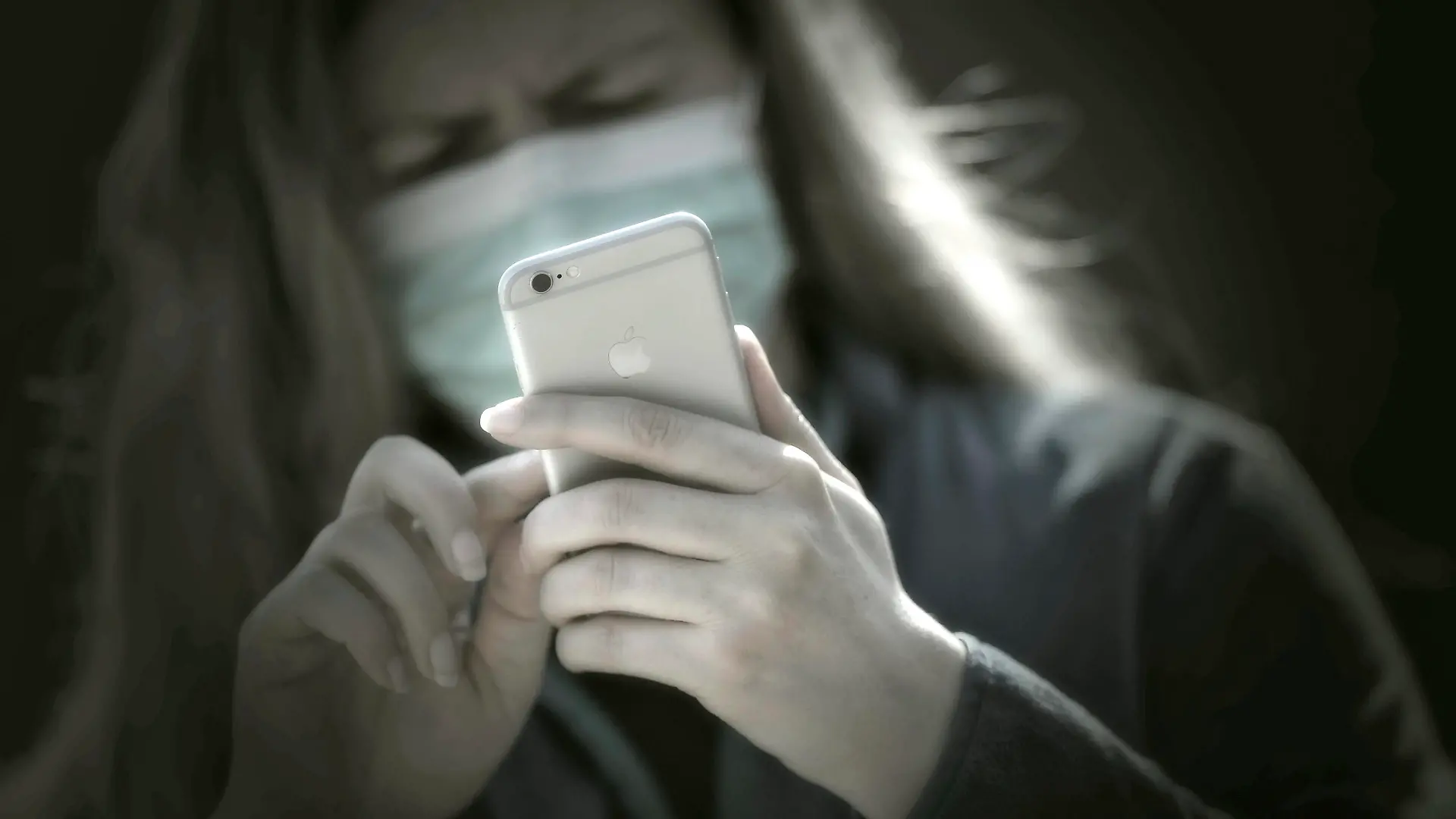  08.04.2020, Symbolbild, Corona-Krise, Frau schaut auf ihr Handy mit Gesichtsmaske. 08.04.2020, Corona-Krise Handy-Nutzung 08.04.2020, Corona-Krise Handy-Nutzung *** 08 04 2020, Symbol picture, Corona crisis, Woman looking at her mobile phone with face mask 08 04 2020, Corona crisis mobile phone use 08 04 2020, Corona crisis mobile phone use