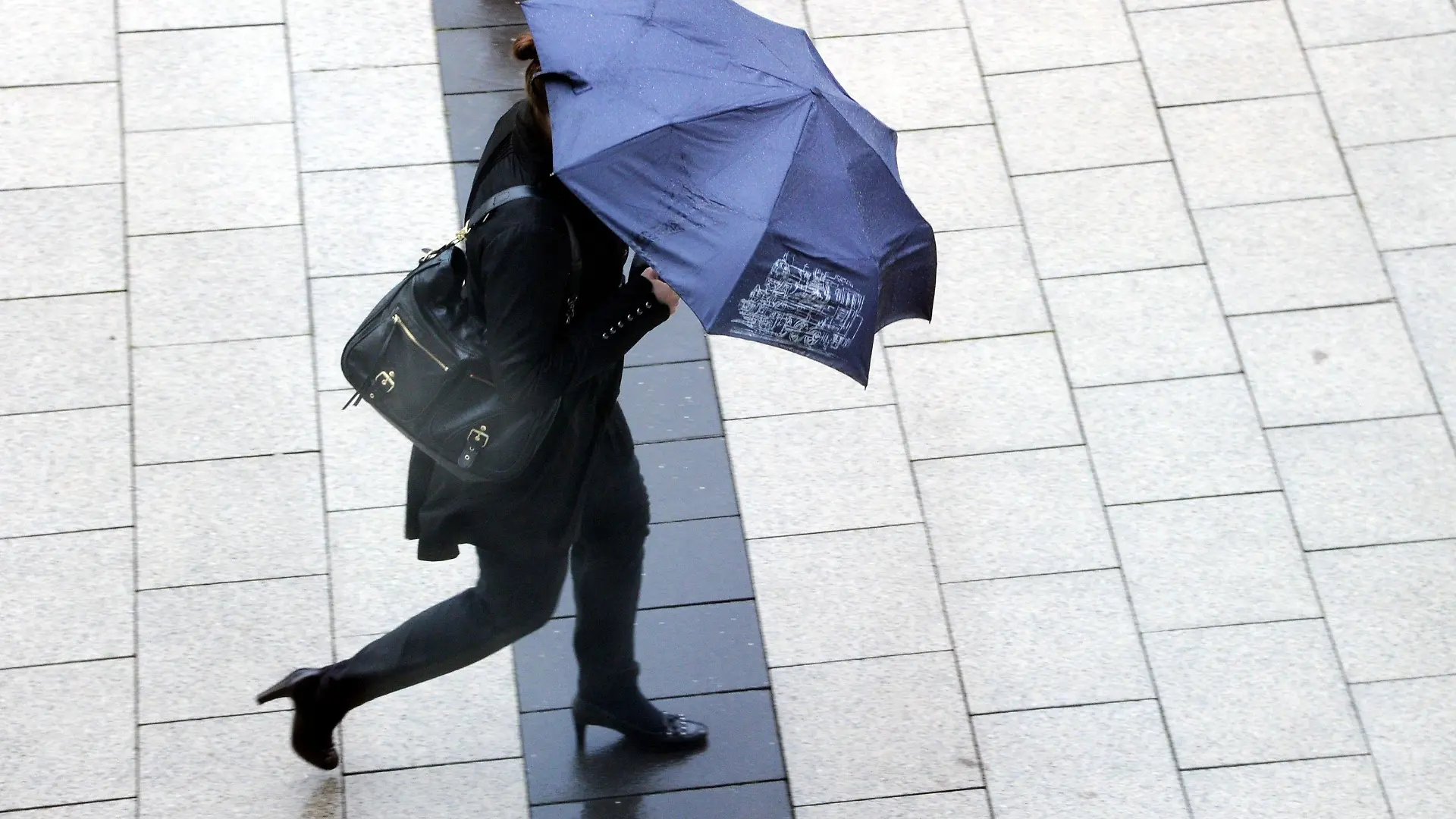 Eine Frau mit Schirm geht am Donnerstag (06.10.2011) durch die Kieler Innenstadt. Das Wetter zeigt sich im Norden mit starkem Wind und Regen sehr herbstlich . Foto: Carsten Rehder dpa/lno +++(c) dpa - Bildfunk+++
