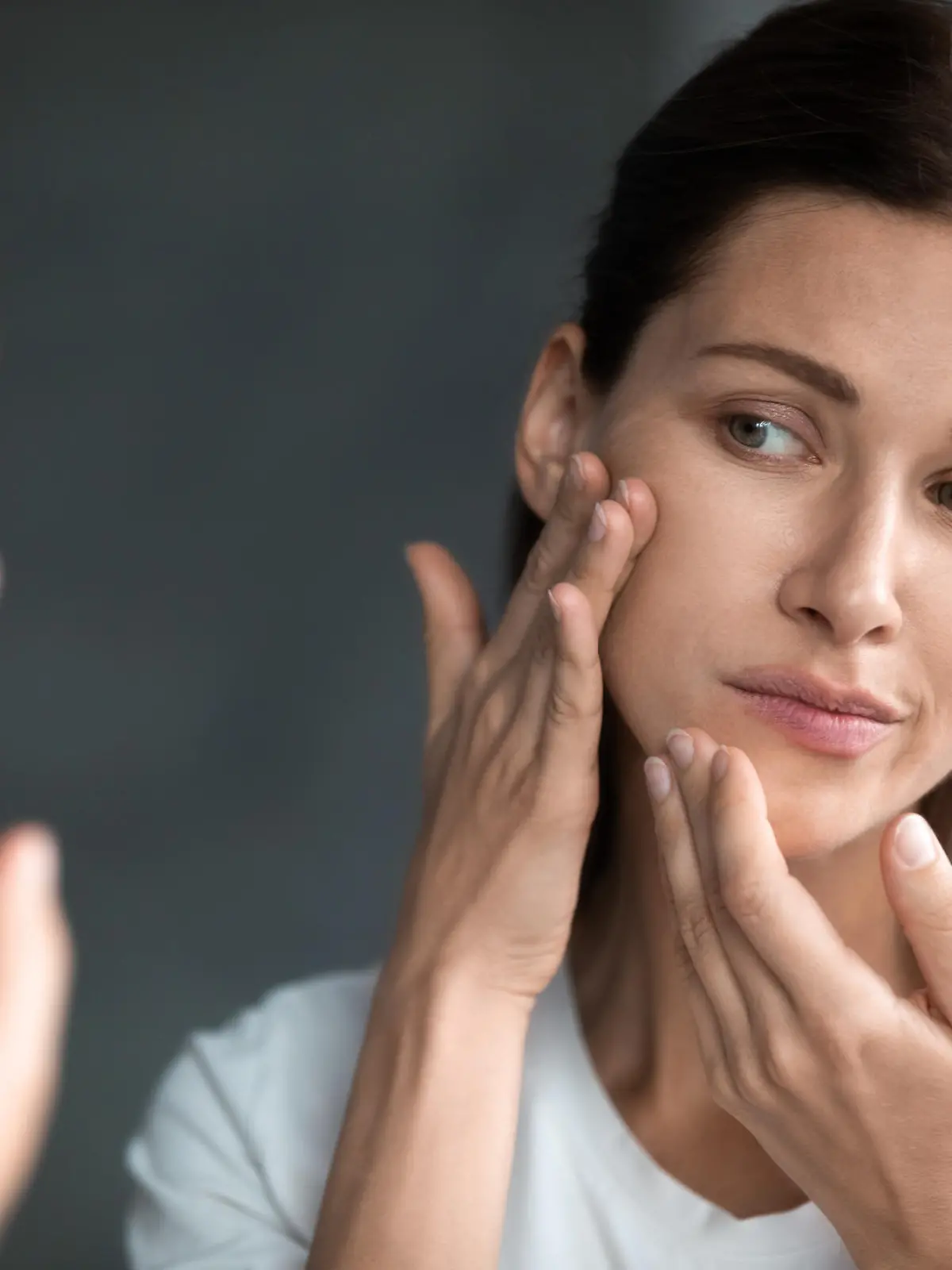 Close up unhappy sad woman looking at red acne spots on chin in mirror, upset young female dissatisfied by unhealthy skin, touching, checking dry irritated face skin, skincare and treatment concept