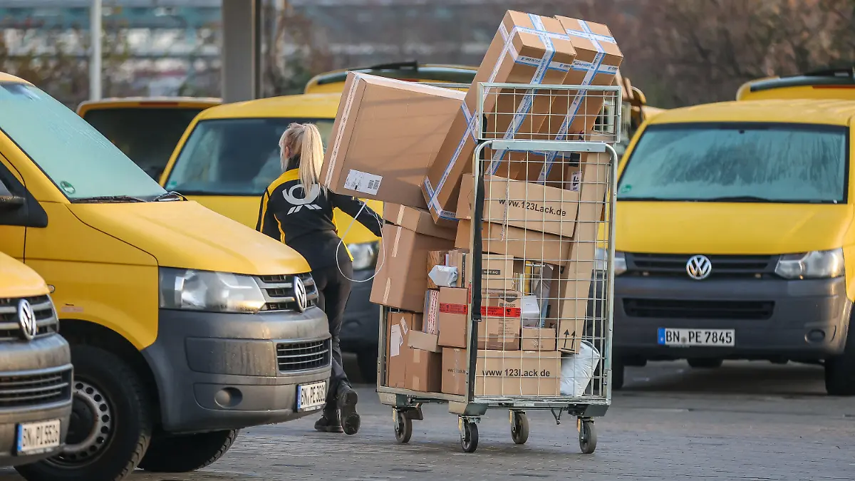 25.11.2022, Sachsen-Anhalt, Bitterfeld-Wolfen: Eine Mitarbeiterin der Deutsche Post DHL zieht einen vollen Paketwagen zu ihren Fahrzeug über den Hof eines Zustellpunktes. Die Wochen vor Weihnachten bedeutet traditionell Hochbetrieb bei den Logistikunternehmen. Tage mit Rabattaktionen wie dem Black Friday steigern das Paketaufkommen zusätzlich. Foto: Jan Woitas/dpa +++ dpa-Bildfunk +++