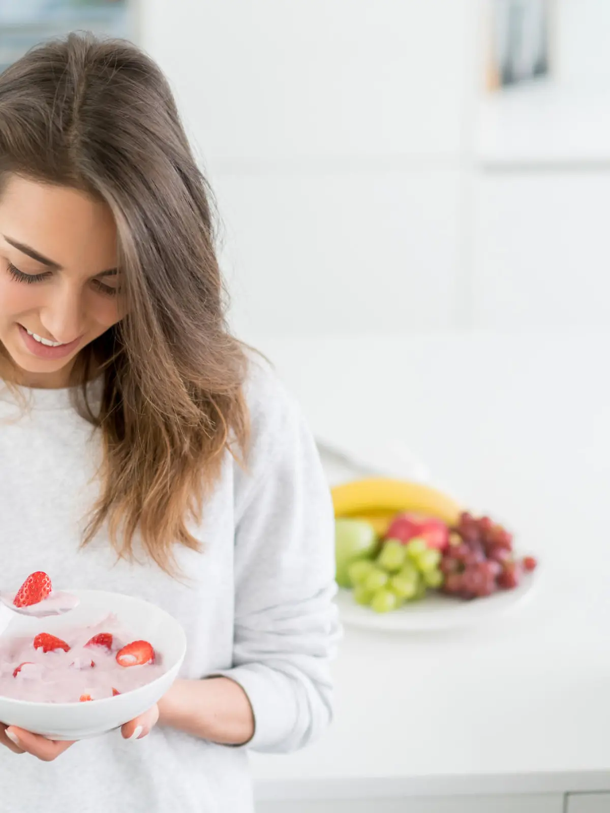 Beautiful young woman eating a healthy breakfast at home and smiling