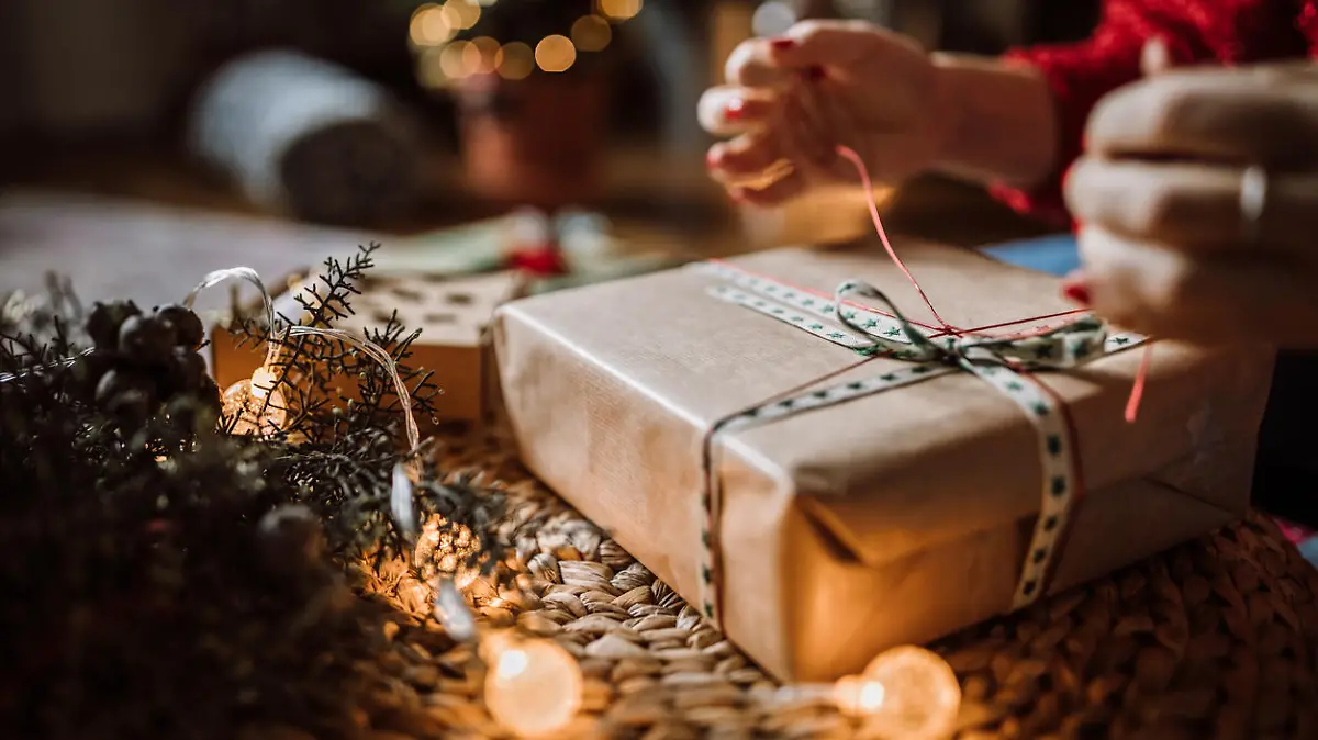Young Woman Wrapping Christmas Gifts In Living Room