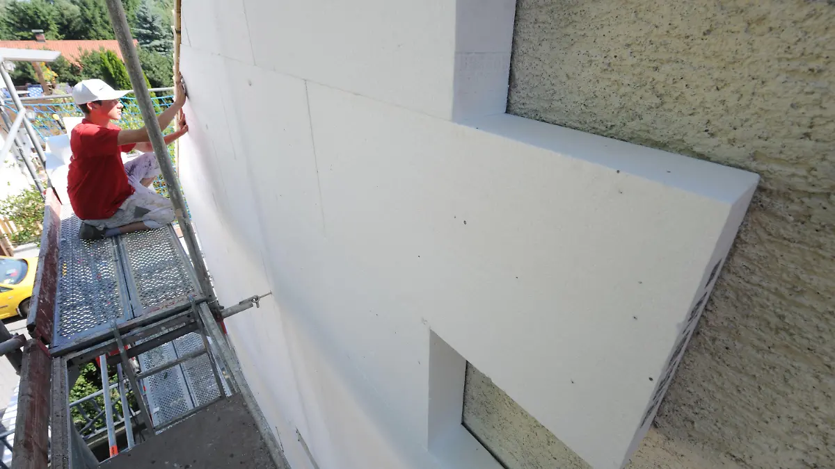 ARCHIV - Ein Fachmann befestigt am 07.07.2010 eine Styroporplatte zur Wärmedämmung an einer Hausfassade in Straubing (Niederbayern). Foto: Armin Weigel dpa (zu dpa "Prognos: Wärmedämmung rechnet sich nicht - Grüne widersprechen=" vom 30.03.2013) +++(c) dpa - Bildfunk+++
