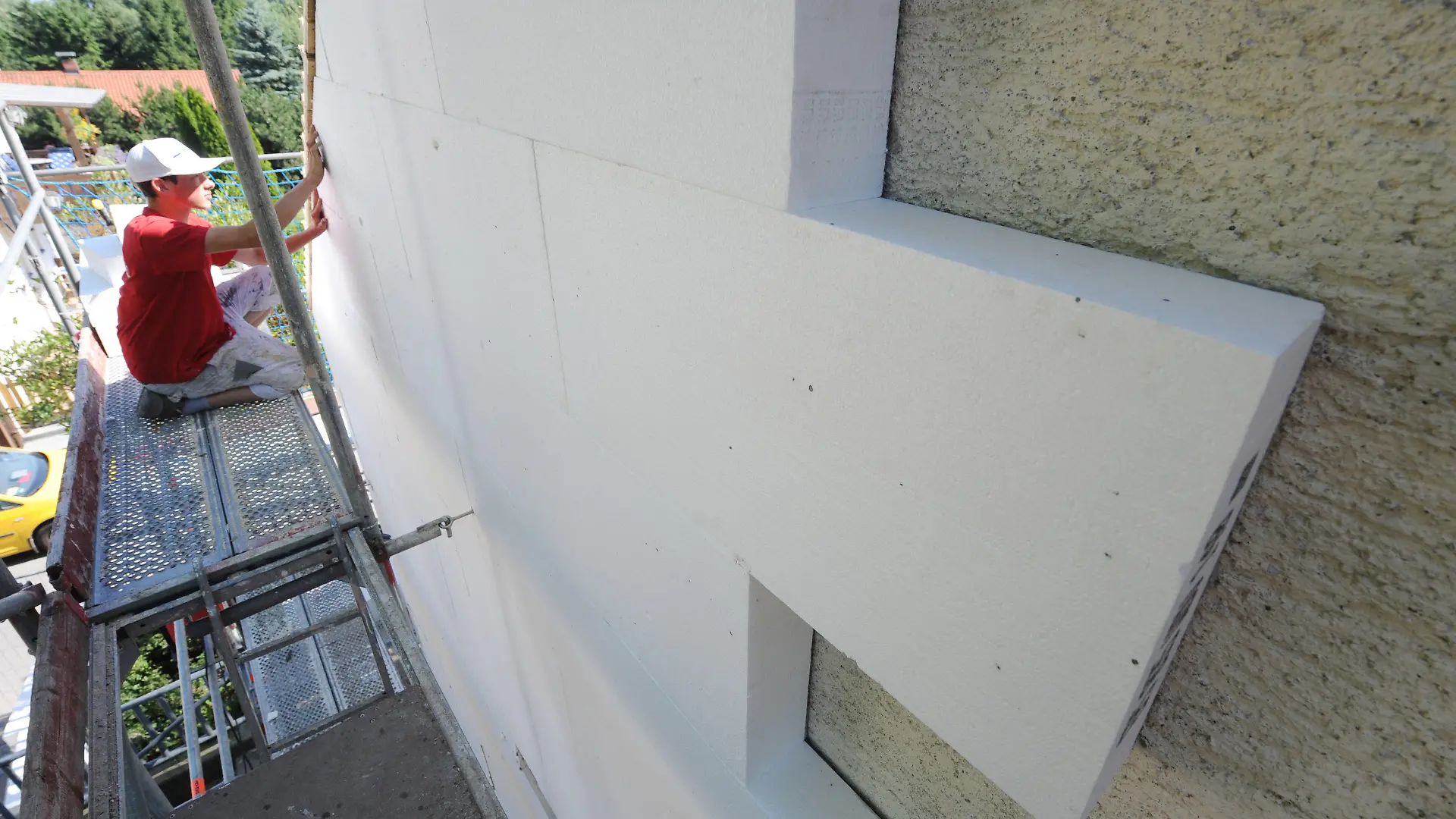 ARCHIV - Ein Fachmann befestigt am 07.07.2010 eine Styroporplatte zur Wärmedämmung an einer Hausfassade in Straubing (Niederbayern). Foto: Armin Weigel dpa (zu dpa "Prognos: Wärmedämmung rechnet sich nicht - Grüne widersprechen=" vom 30.03.2013) +++(c) dpa - Bildfunk+++