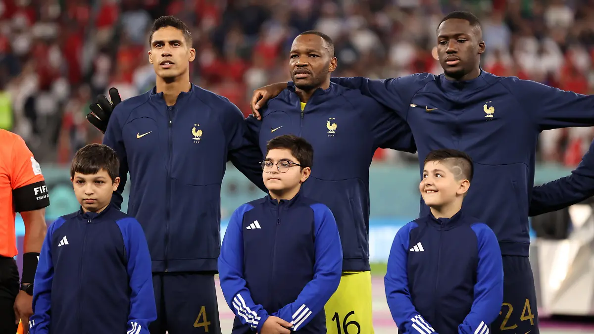AL RAYYAN, QATAR - NOVEMBER 30: Raphael Varane, Steve Mandanda and Ibrahima Konate of France sing their national anthem prior to the FIFA World Cup Qatar 2022 Group D match between Tunisia and France at Education City Stadium on November 30, 2022 in Al Rayyan, Qatar. (Photo by Ryan Pierse/Getty Images)