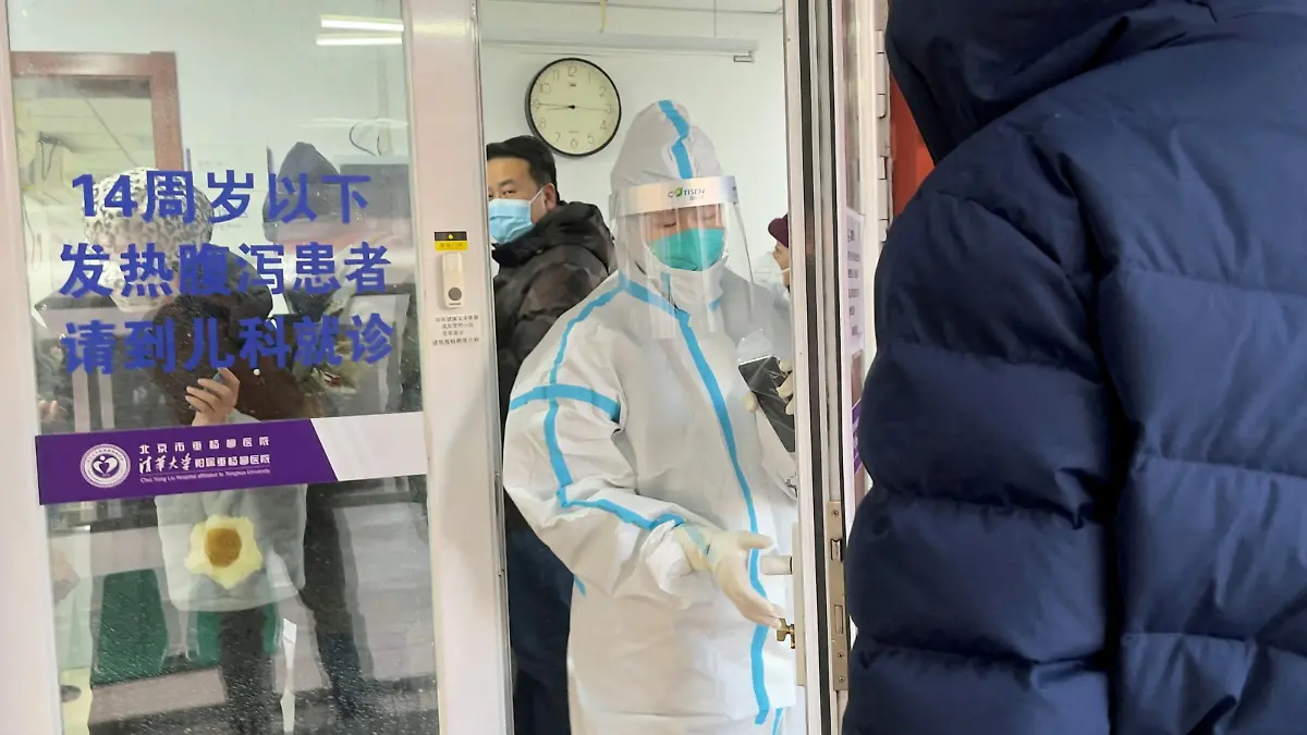 People line up next to a medical worker in a protective suit, at a fever clinic of a hospital amid the coronavirus disease (COVID-19) outbreak in Beijing, China December 15, 2022. REUTERS/Josh Arslan