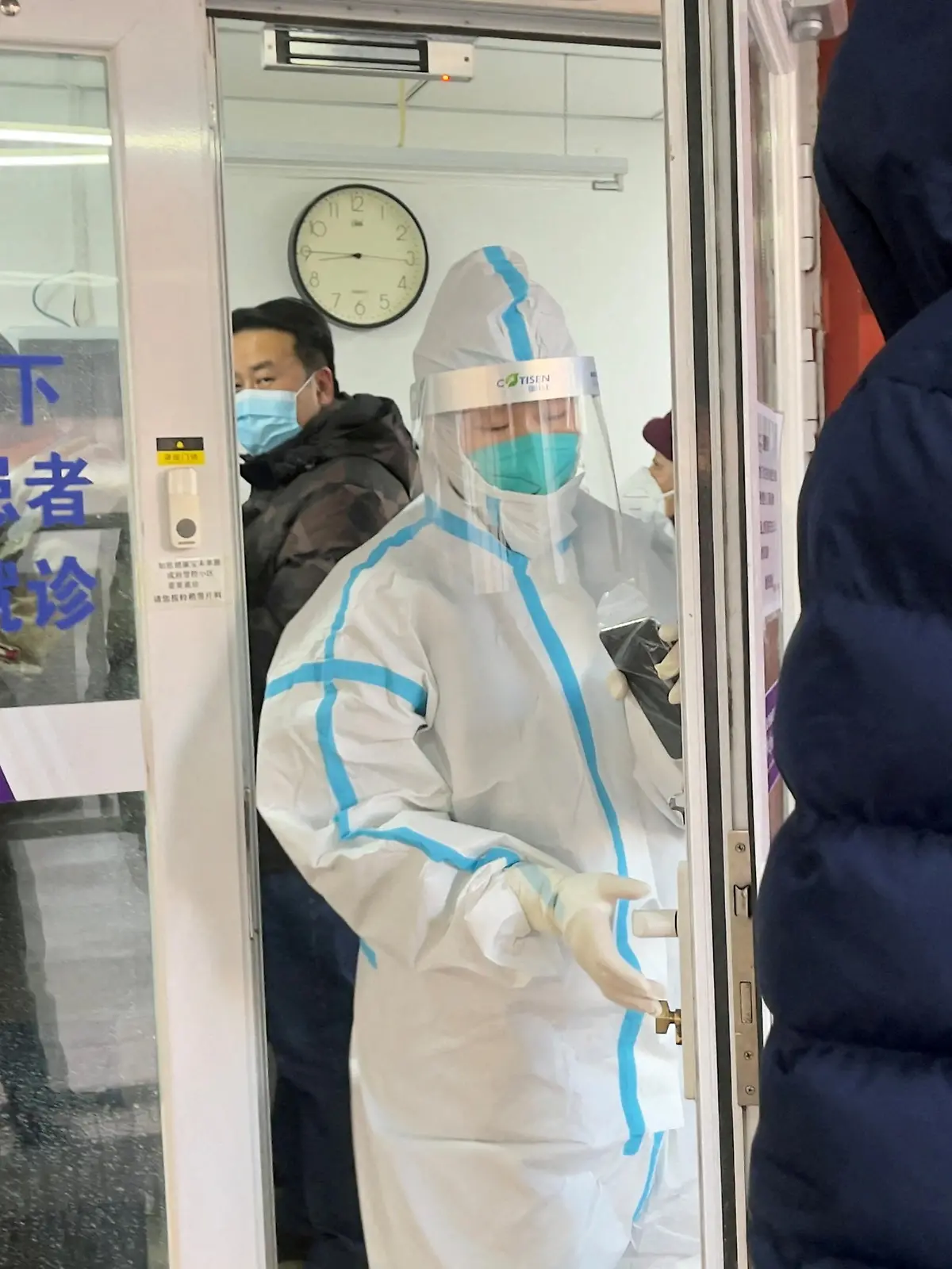 People line up next to a medical worker in a protective suit, at a fever clinic of a hospital amid the coronavirus disease (COVID-19) outbreak in Beijing, China December 15, 2022. REUTERS/Josh Arslan