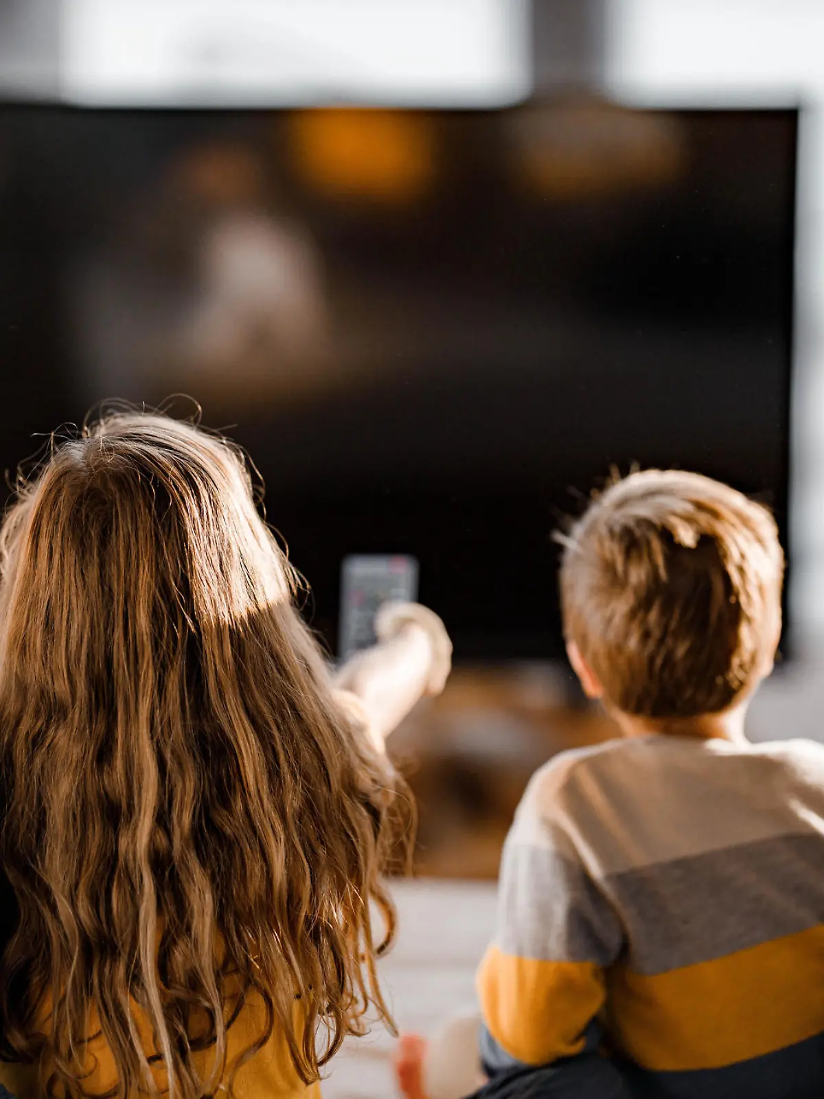 Rear view of a relaxed family watching a movie in the living room.