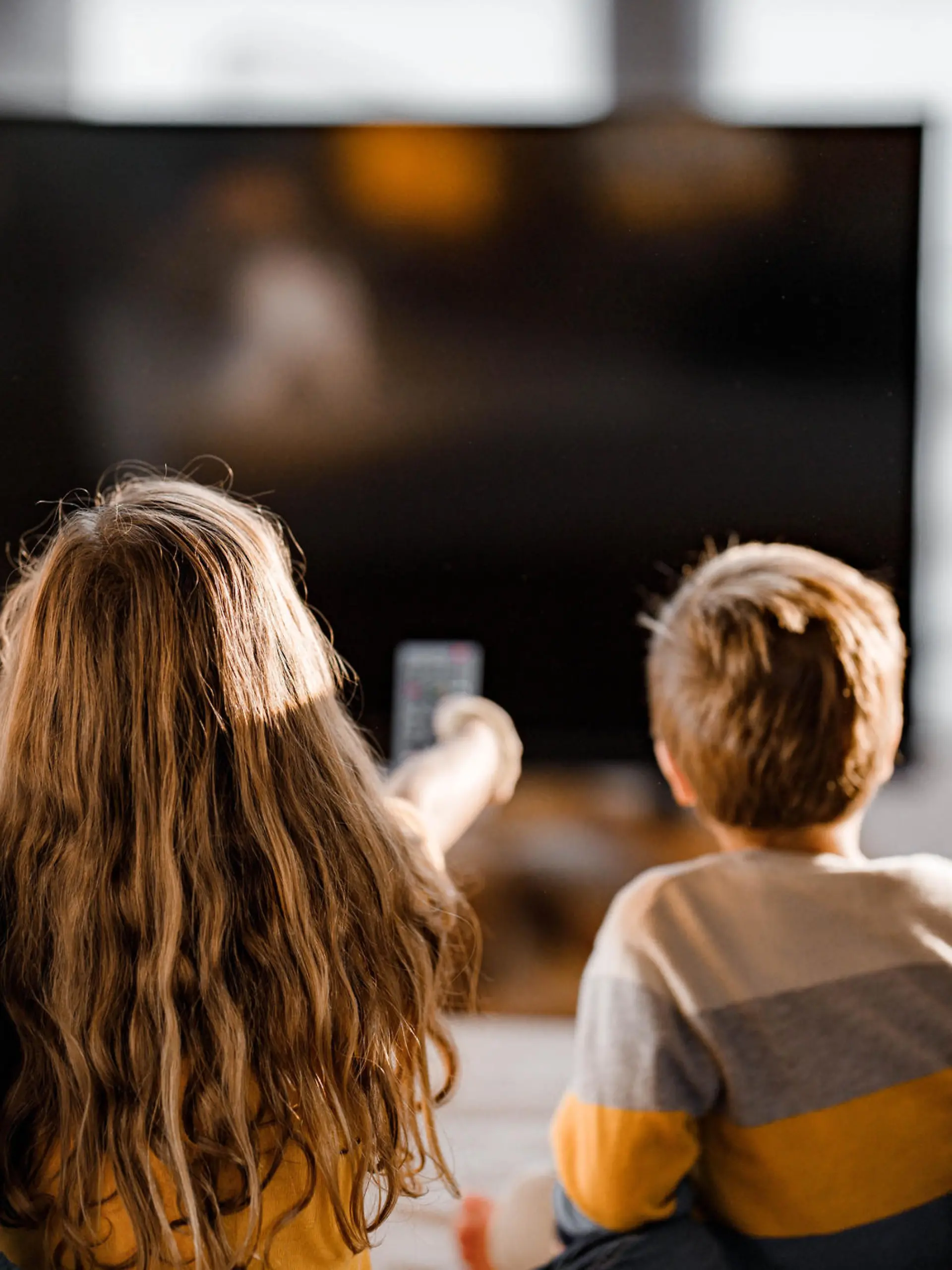 Rear view of a relaxed family watching a movie in the living room.