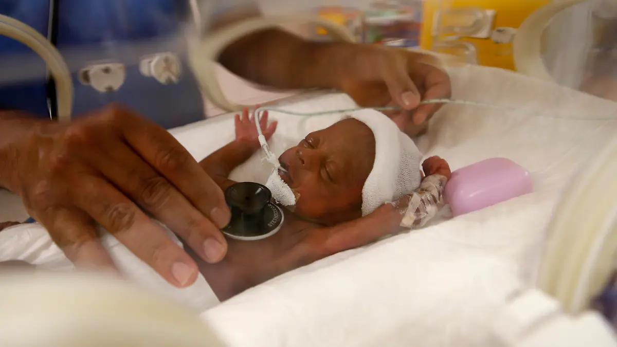 Paediatrician Dr. Msayif Khali examines with a stethoscope one of the nine babies protected in an incubator at the maternity unit of the Ain Borja clinic in Casablanca, Morocco, Thursday May 20, 2021, two weeks after Mali's Halima Cisse, 25, gave birth to nine healthy babies. (AP Photo/Abdeljalil Bounhar)
