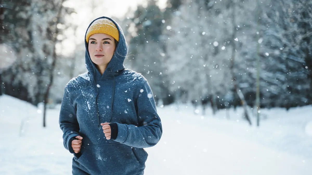 Running woman during her jogging workout during winter and snowy day