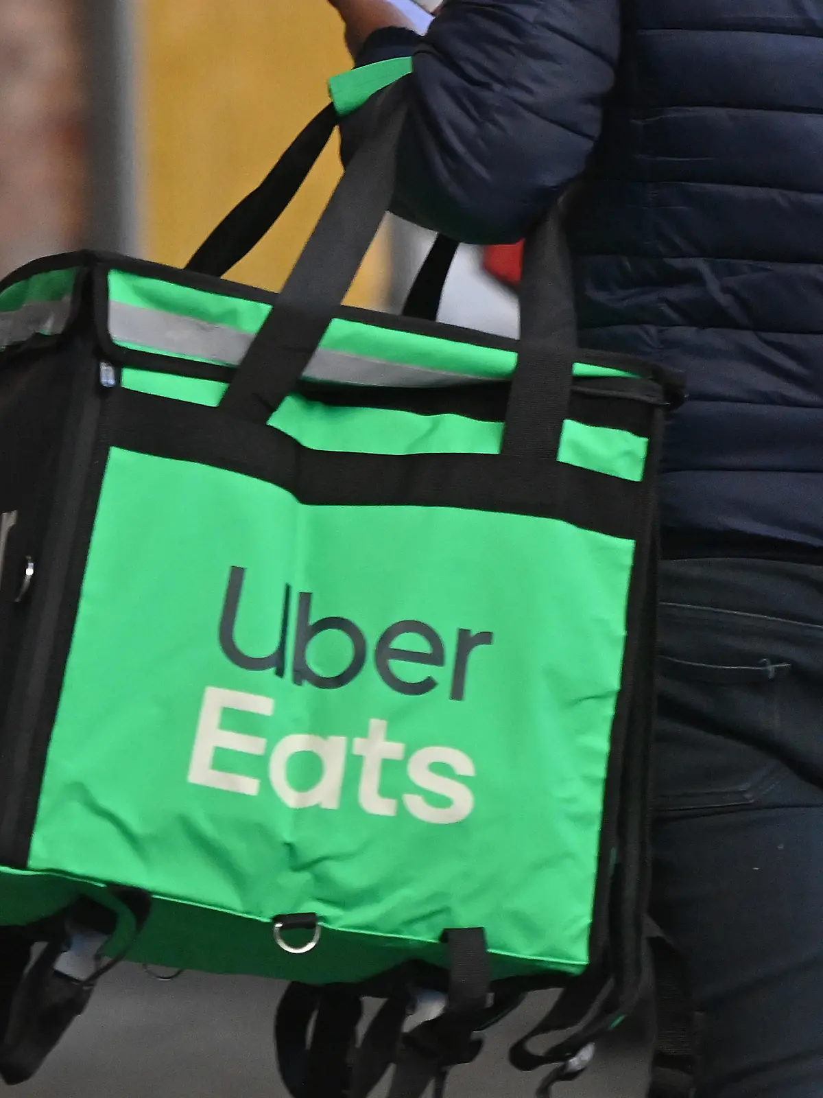UberEats Essenslieferung,Ein Mann traegt eine Isoliertasche mit warmen Mahlzeiten. Ein