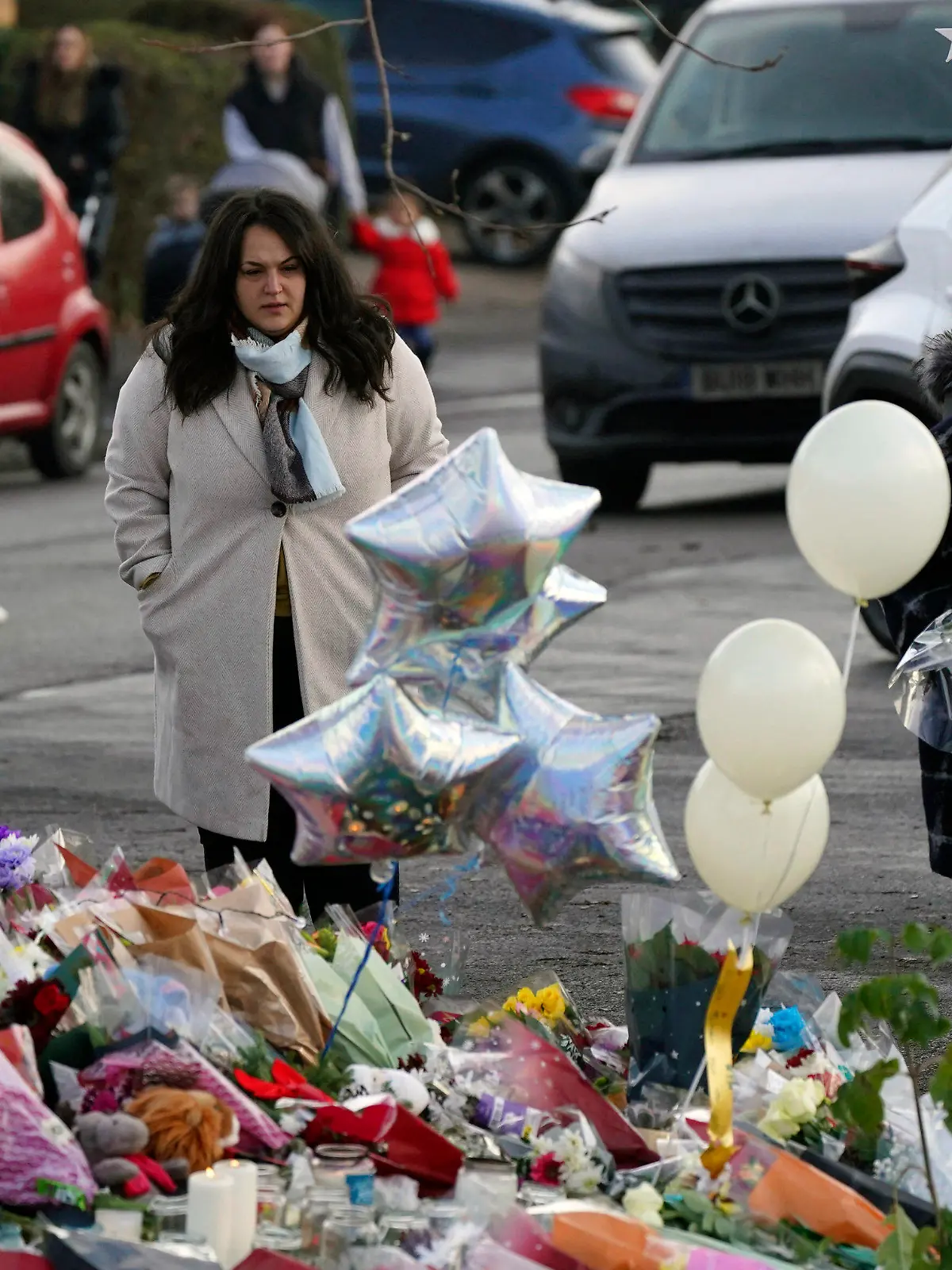 People look at flowers and tributes near to Babbs Mill Park in Kingshurst, Solihull, Tuesday Dec. 13, 2022 after the deaths of three boys aged eight, 10 and 11 who fell through ice into a lake in the West Midlands. (Jacob King/PA via AP)