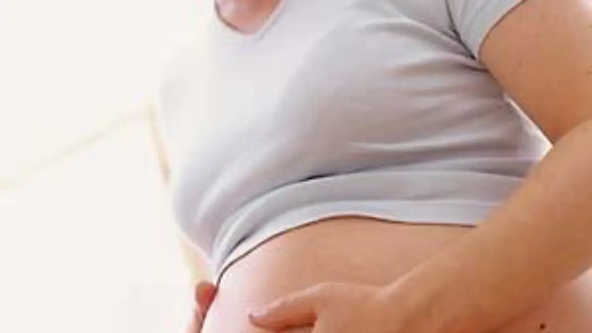 Schwangere Frau haelt sich den nackten Bauch.
