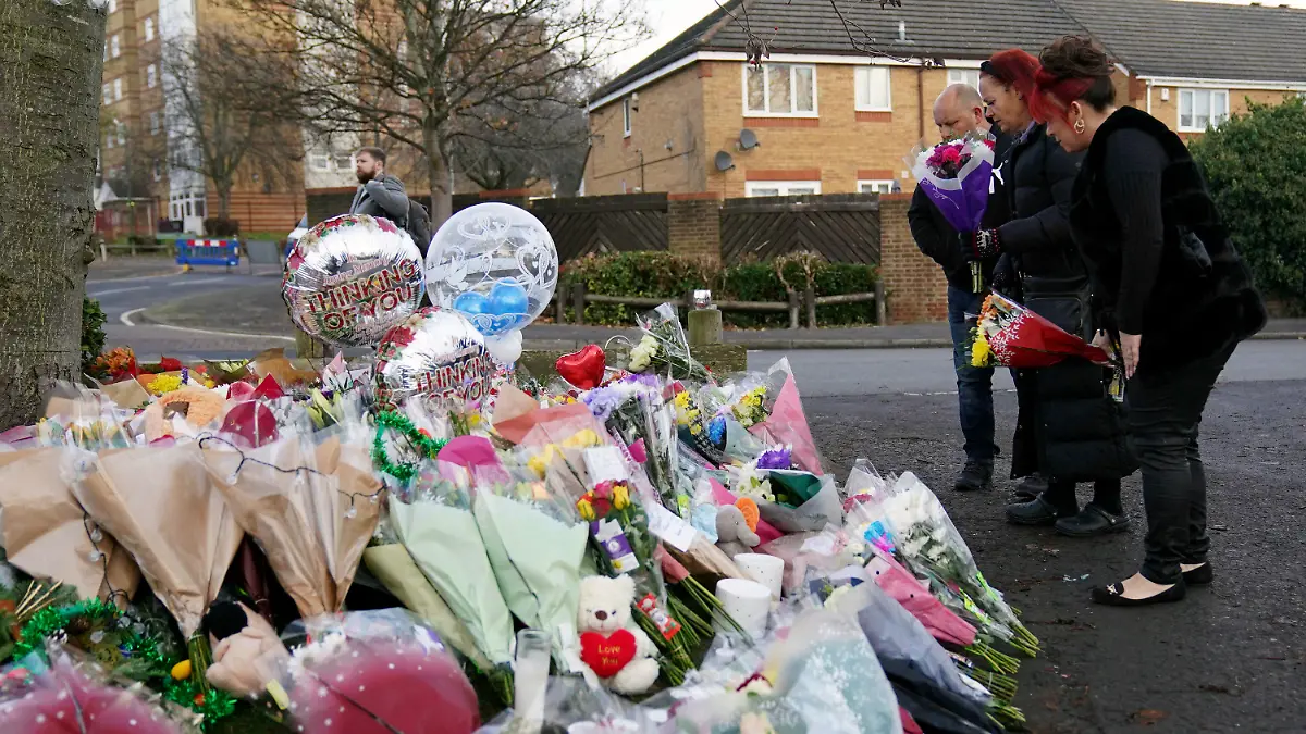 Woman lay flowers among the tributes near to Babbs Mill Park in Kingshurst, Solihull, Tuesday Dec. 13, 2022 after the deaths of three boys aged eight, 10 and 11 who fell through ice into a lake in the West Midlands. (Jacob King/PA via AP)