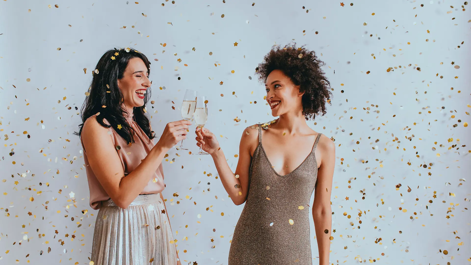 Party time: two elegant young women drinking champagne to celebrate together.