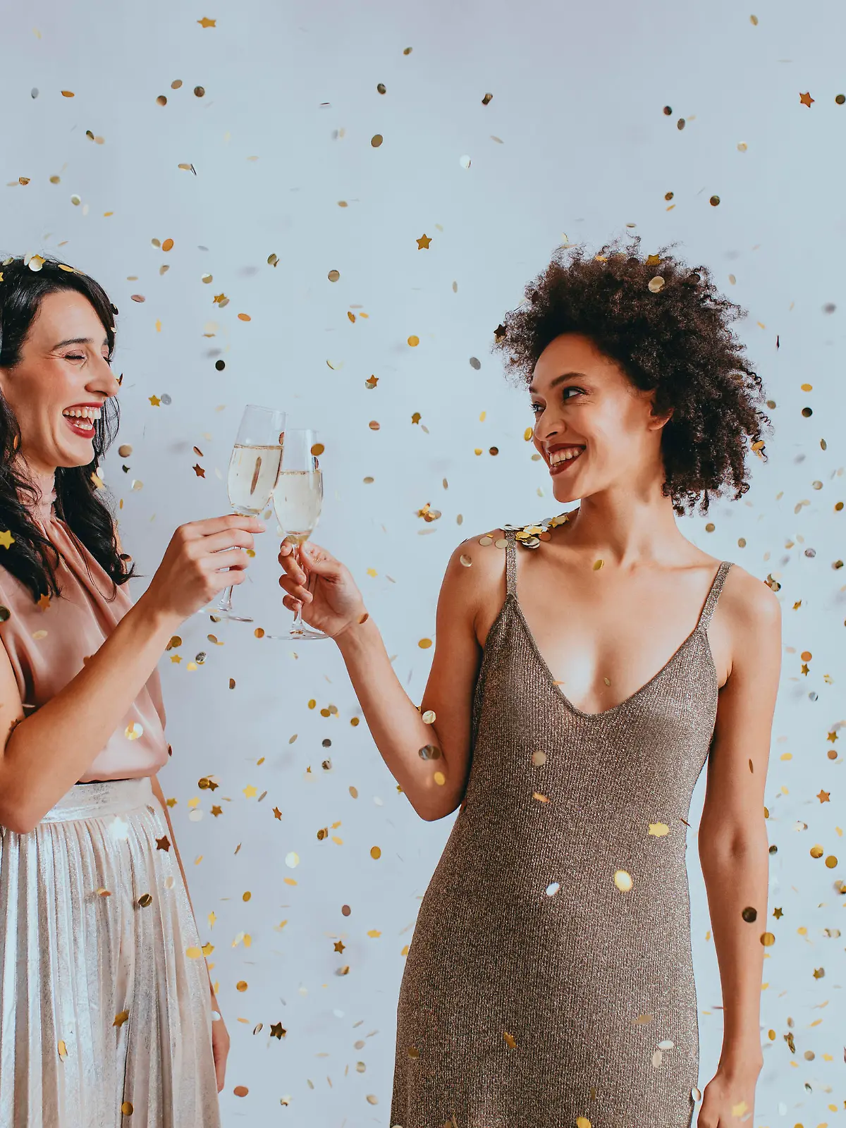 Party time: two elegant young women drinking champagne to celebrate together.