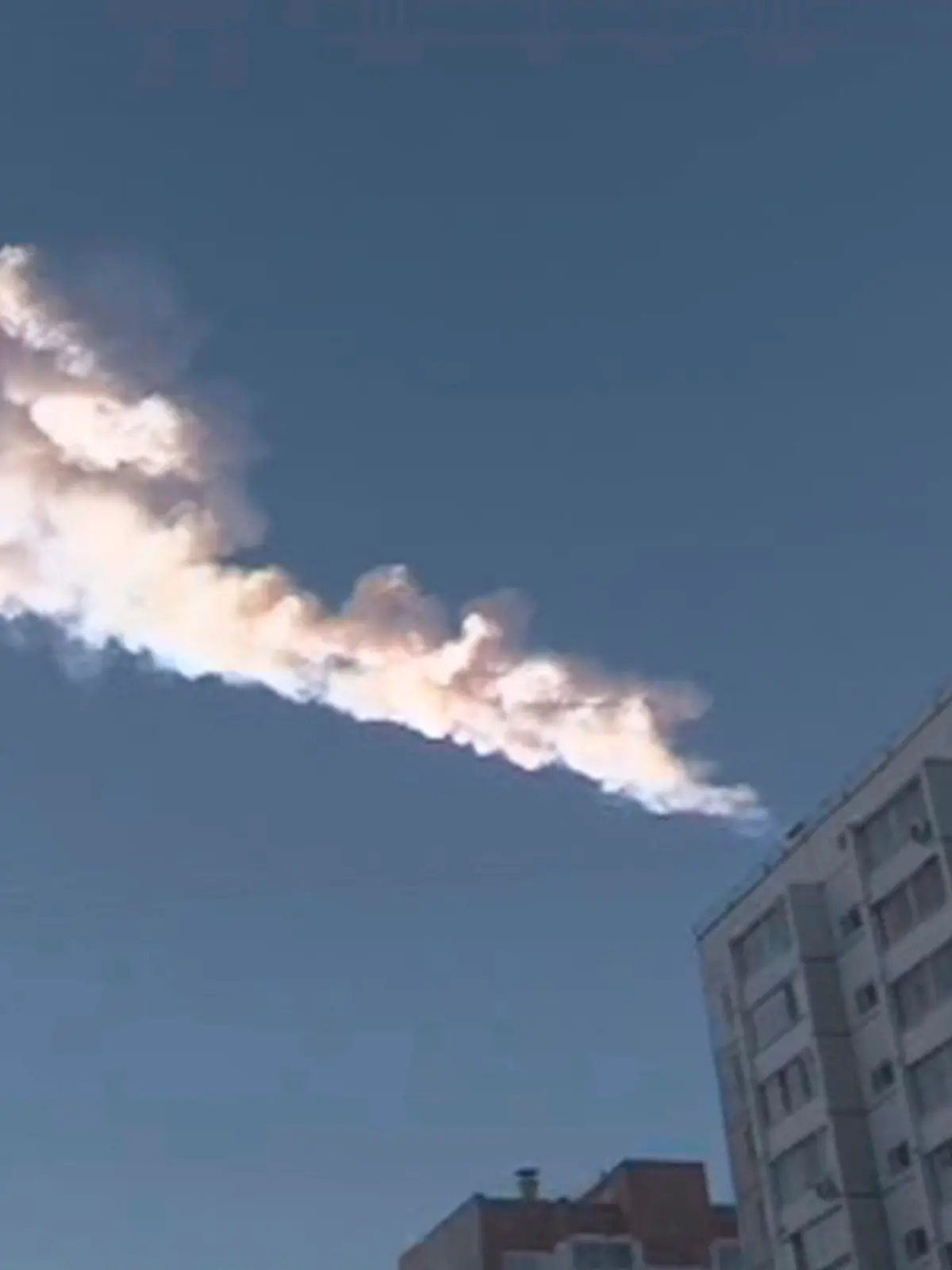 The trail of a falling object is seen above a residential apartment block in the Urals city of Chelyabinsk, in this still image taken from video shot on February 15, 2013. A powerful blast rocked the Russian region of the Urals early on Friday with bright objects, identified as possible meteorites, falling from the sky, emergency officials said. REUTERS/OOO Spetszakaz (RUSSIA - Tags: ENVIRONMENT TPX IMAGES OF THE DAY)
