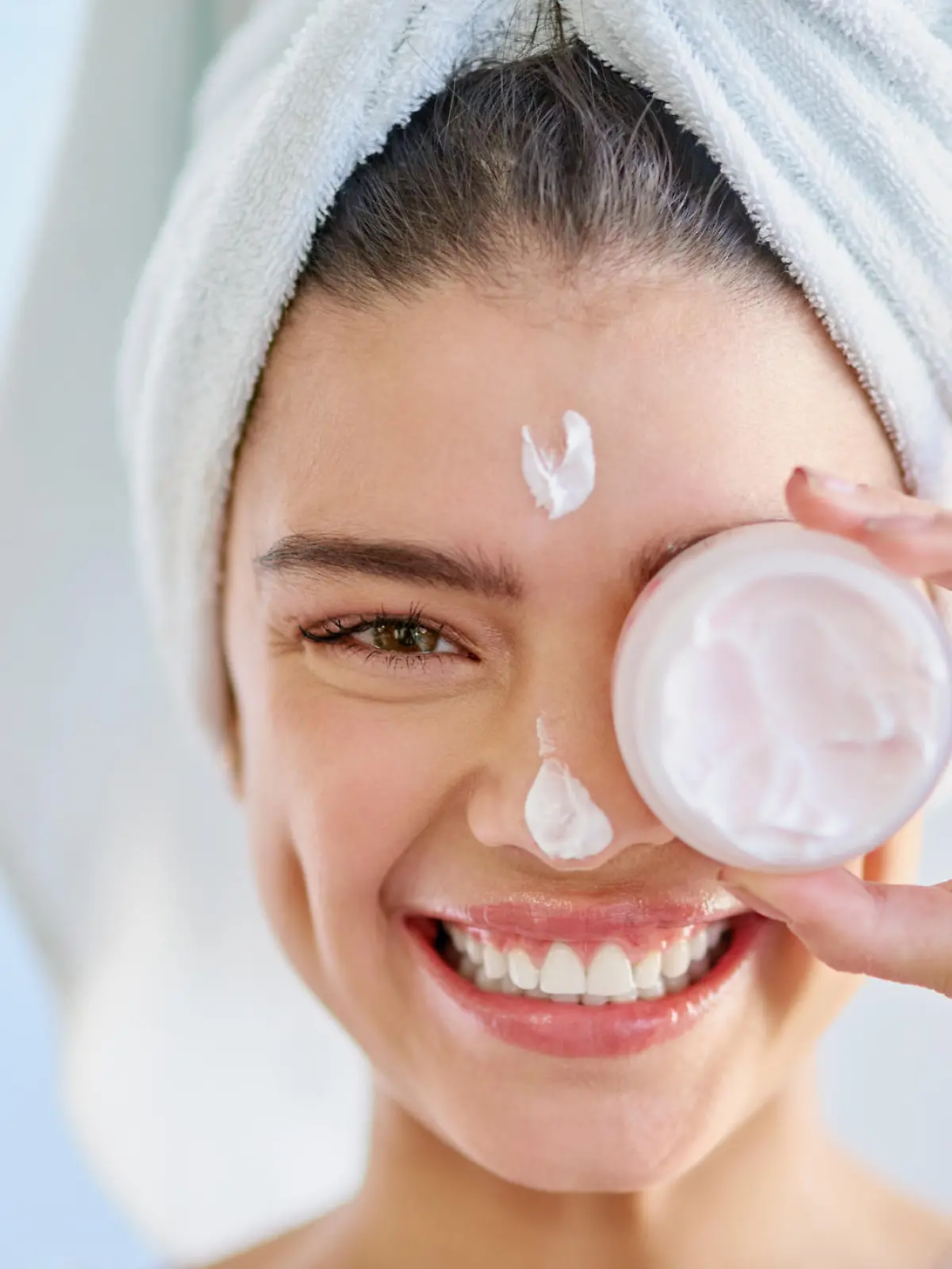 Cropped portrait of a beautiful young woman applying moisturizer to her skin in the bathroom at home
